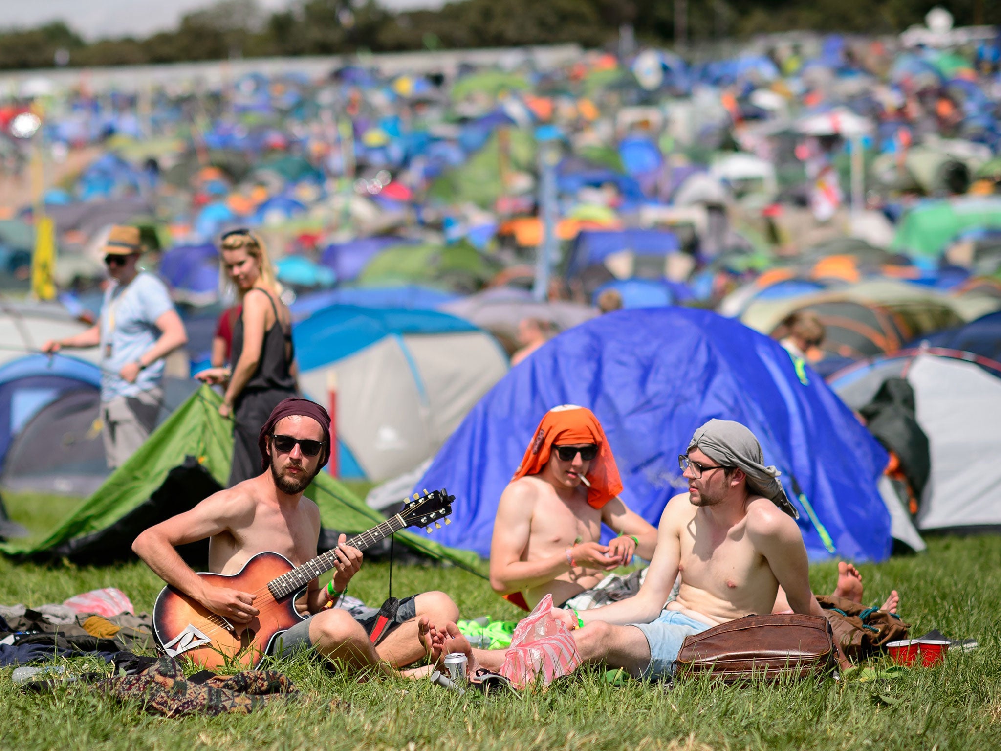 People sit in the sunshine as the Glastonbury Festival