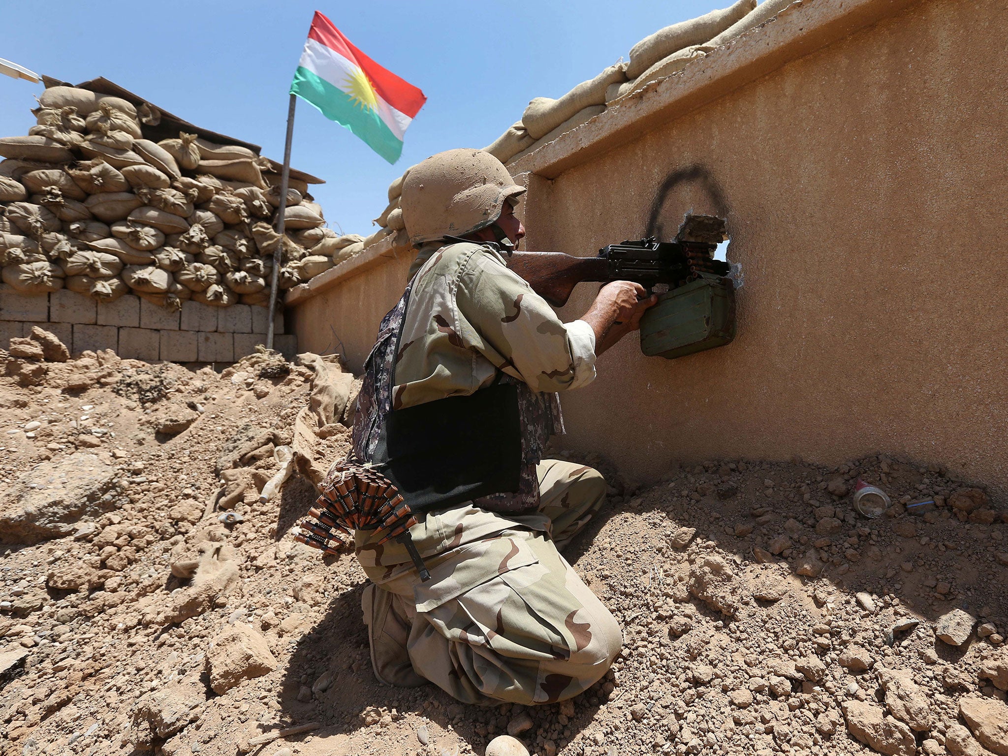 A Kurdish peshmerga fighter takes his position behind a wall on the front line with militants from the Isis group, in Tuz Khormato, 100 kilometers (62 miles) south of the oil rich province of Kirkuk