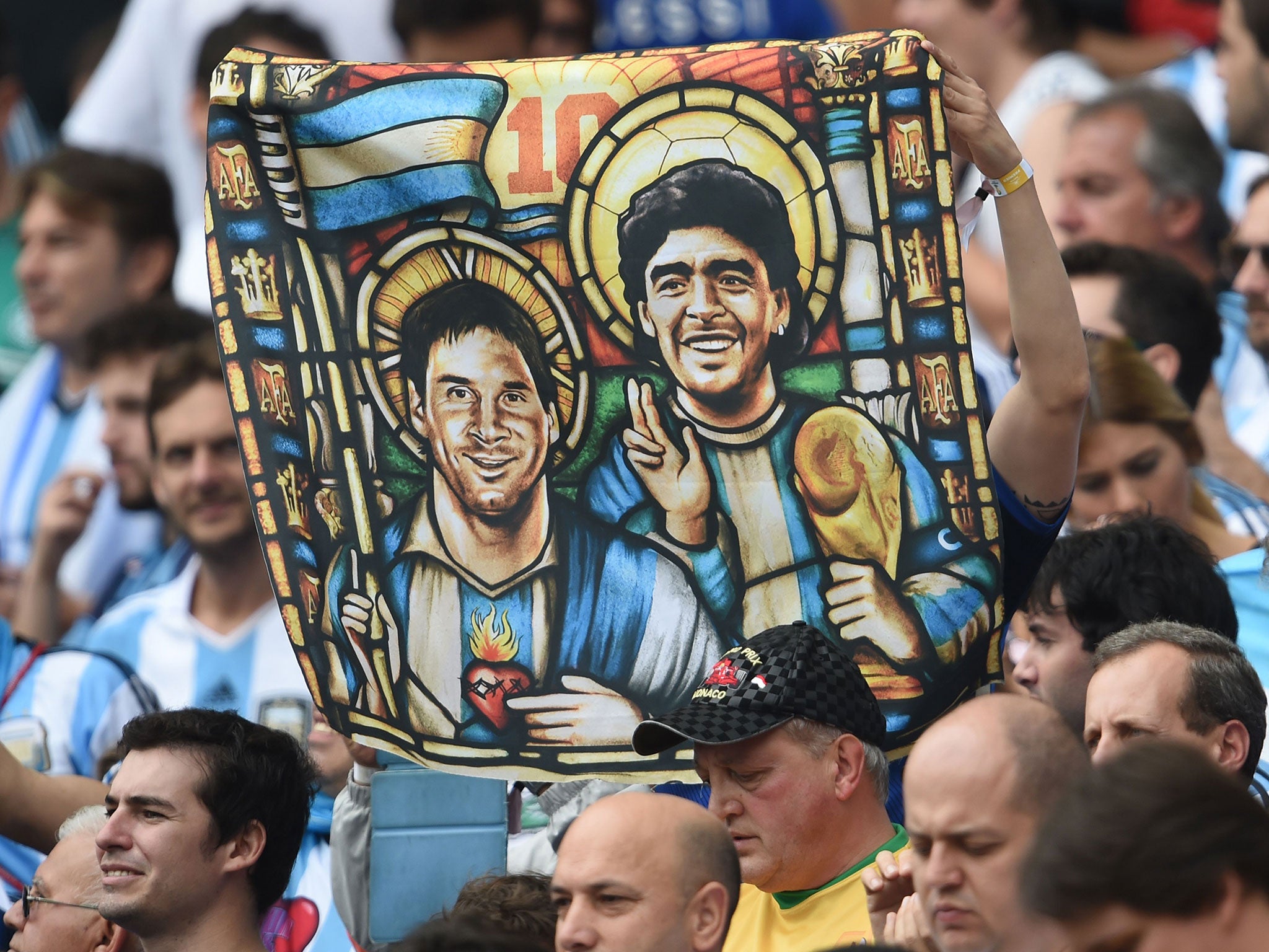 An Argentina's fan holds an image of Argentina's forward Lionel Messi and former footballer Diego Maradona as Saints, before for the Group F football match between Nigeria and Argentina at the Beira-Rio Stadium in Porto Alegre during the 2014 FIFA World C