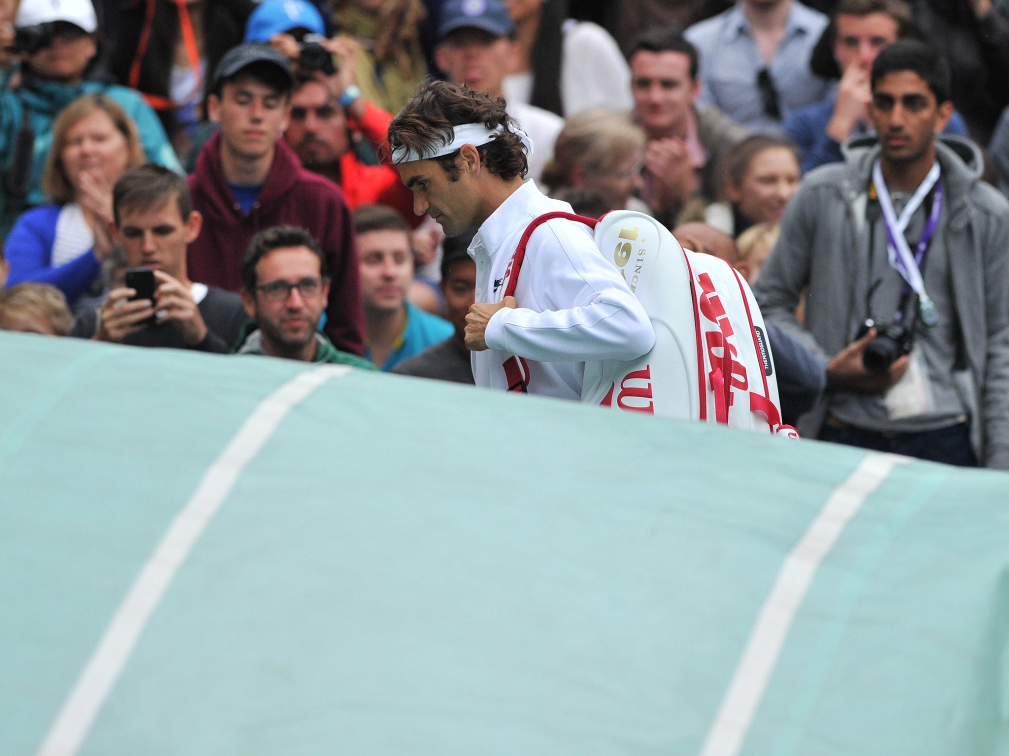 Roger Federer heads off Centre Court to await the roof to come over during his win over Gilles Muller