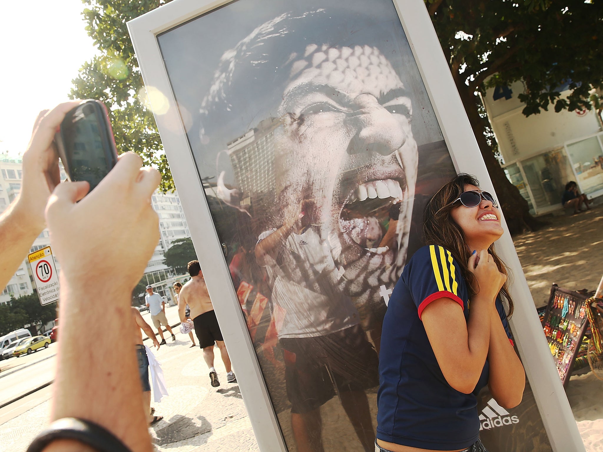 A woman takes a photo next to an advertisement featuring Uruguay's Luis Suarez, mocking the biting incident
