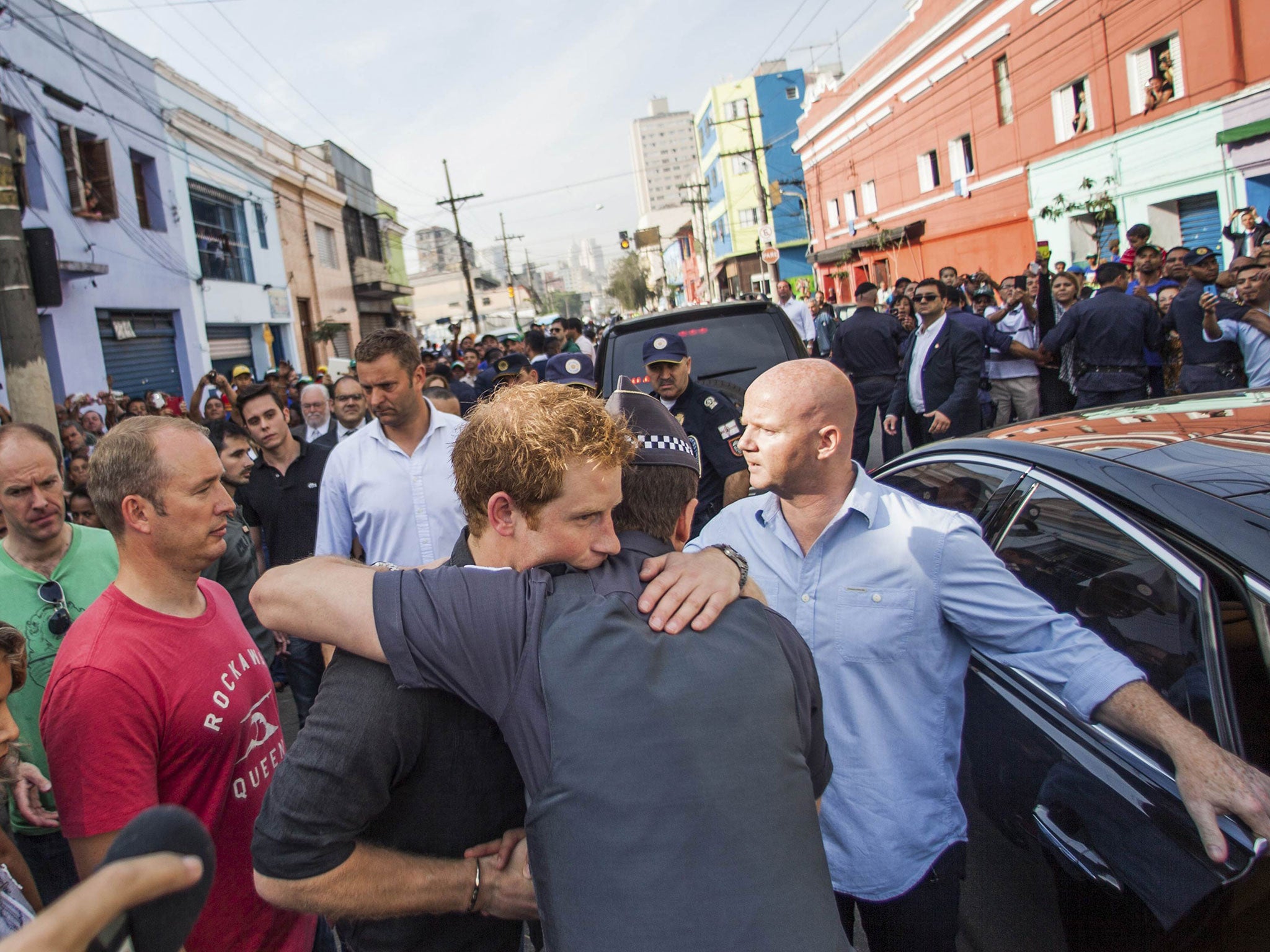 Prince Harry (C) embraces a resident during a visit to Sao Paulo's Luz neighborhood known to locals as Cracolandia (Crackland)