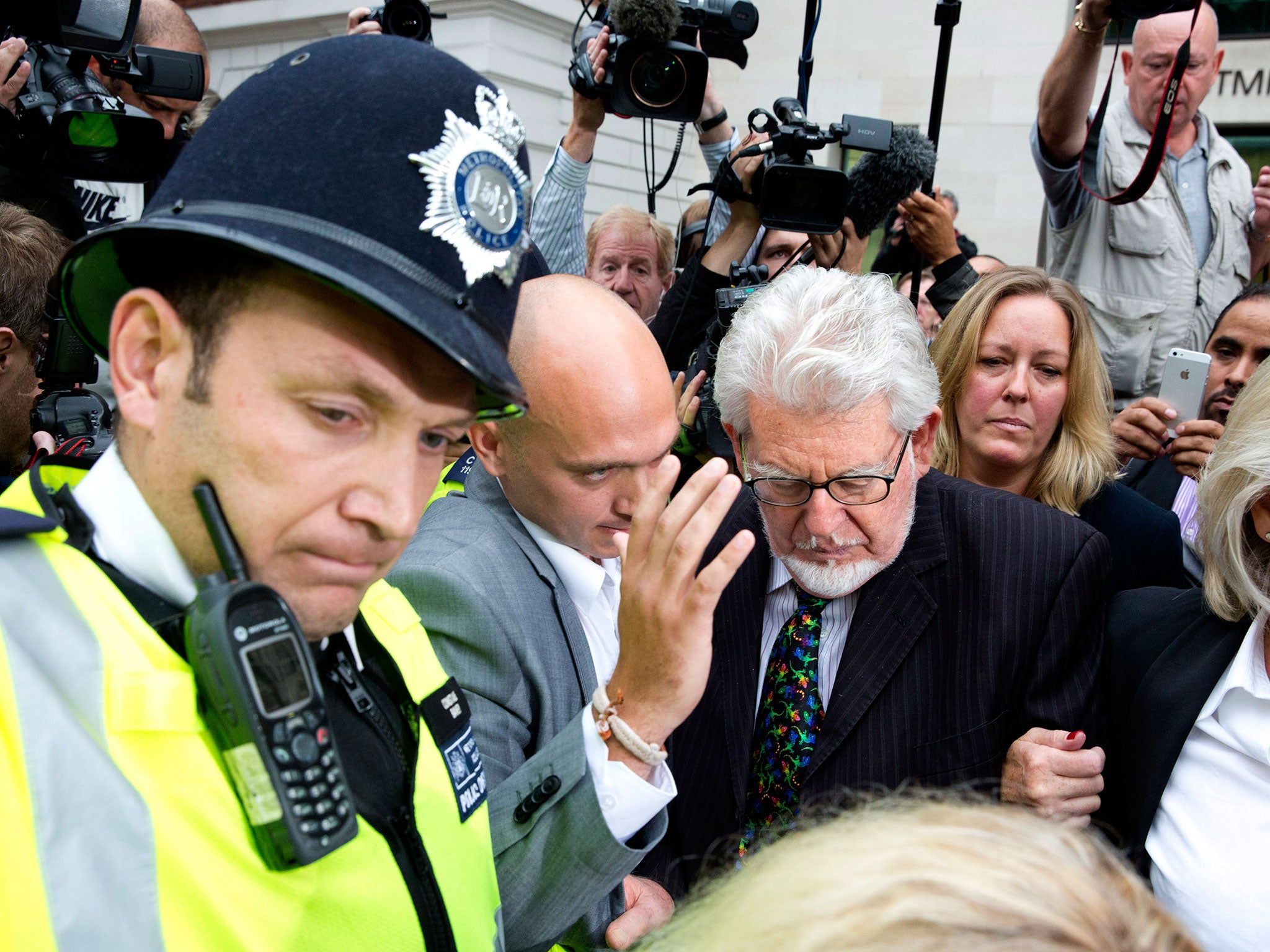 Rolf Harris is surrounded by members of the media as he leaves Westminster Magistrates Court, in central London, 2013