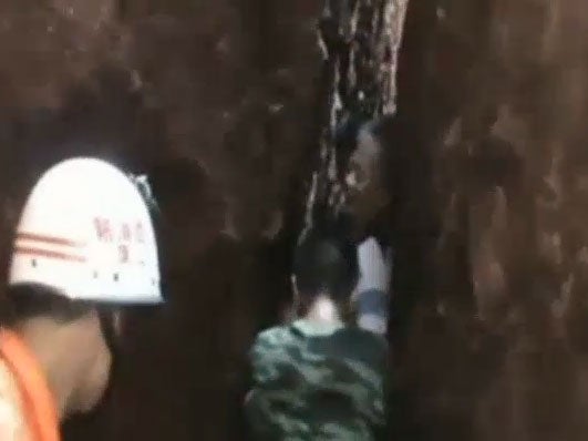 Rescue workers struggle their way to reach a tourist who is trapped in a cliff gap in east China.