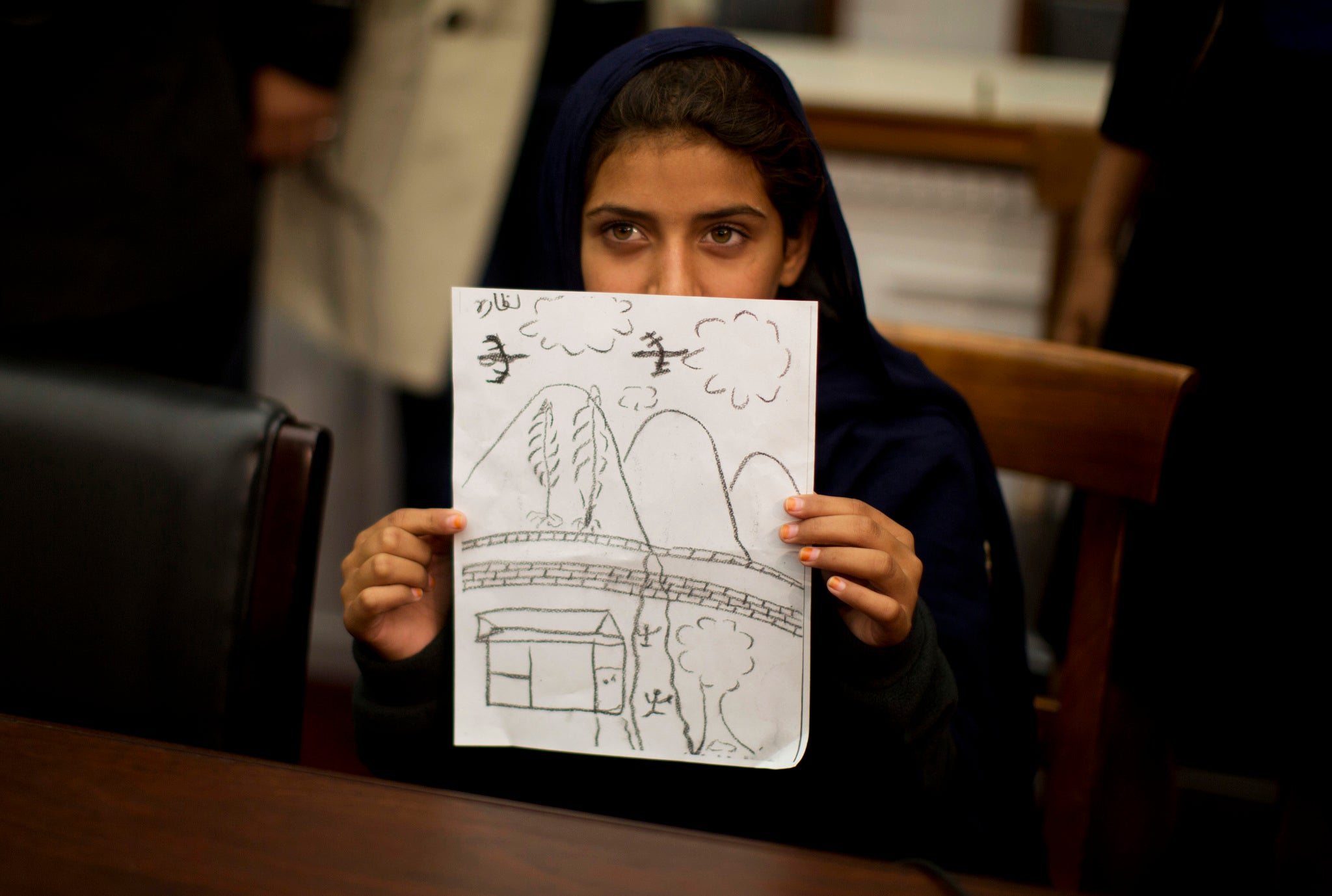 Nabila Rehman, 9, holds up a picture she drew depicting the U.S. drone strike on her Pakistan village which killed her grandmother Mammana Bibi.