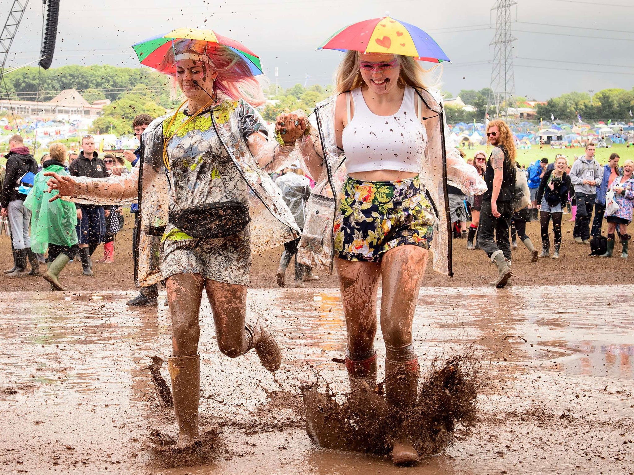 Girls run through a muddy puddle at the Glastonbury Festival