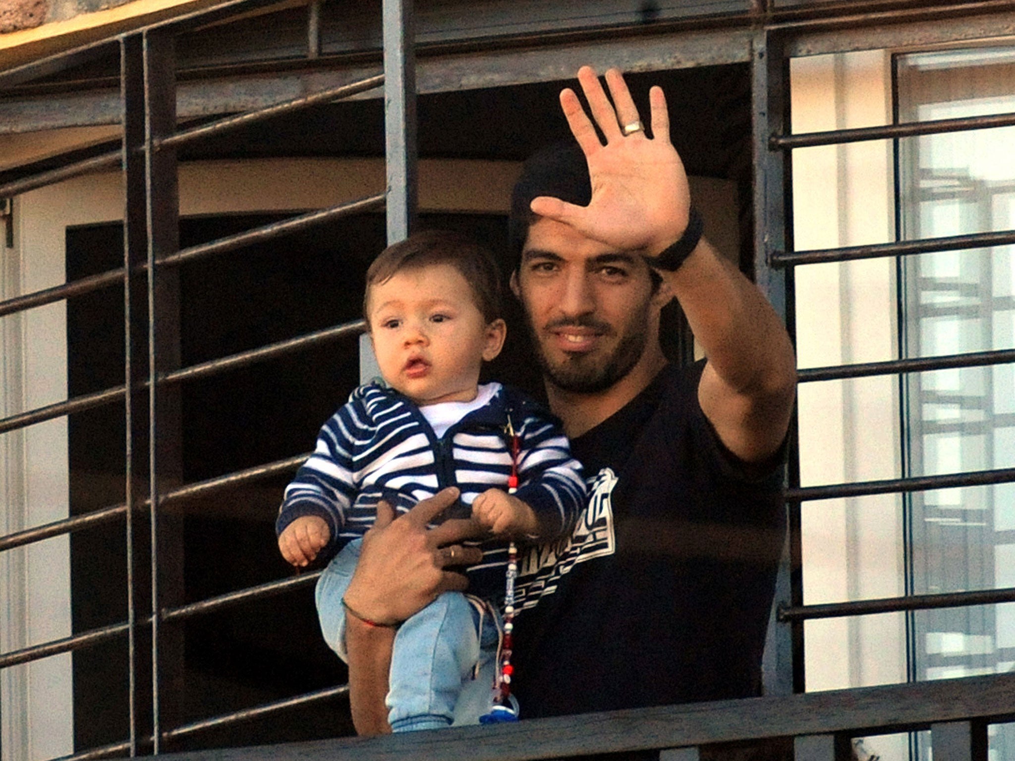 Luis Suarez greets fans waiting outside his house in Lagomar, near Montevideo