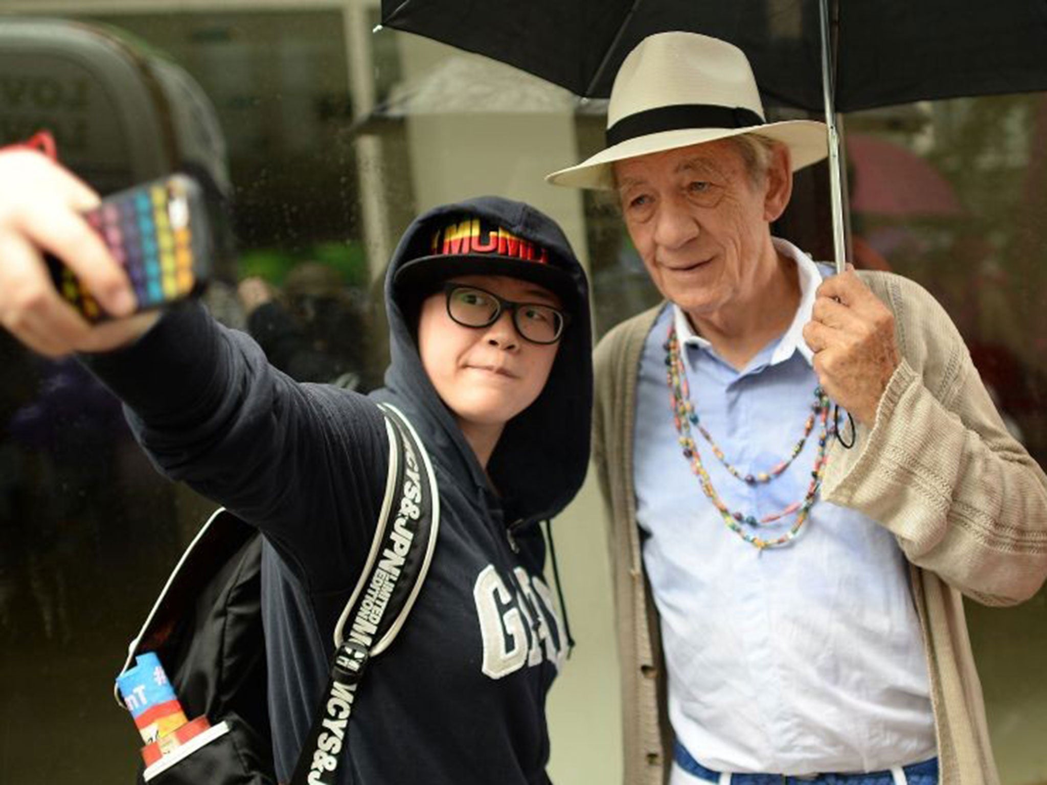 British actor Ian McKellan, right poses for a selfie with a reveler at the London Pride Parade 2014 in central London.