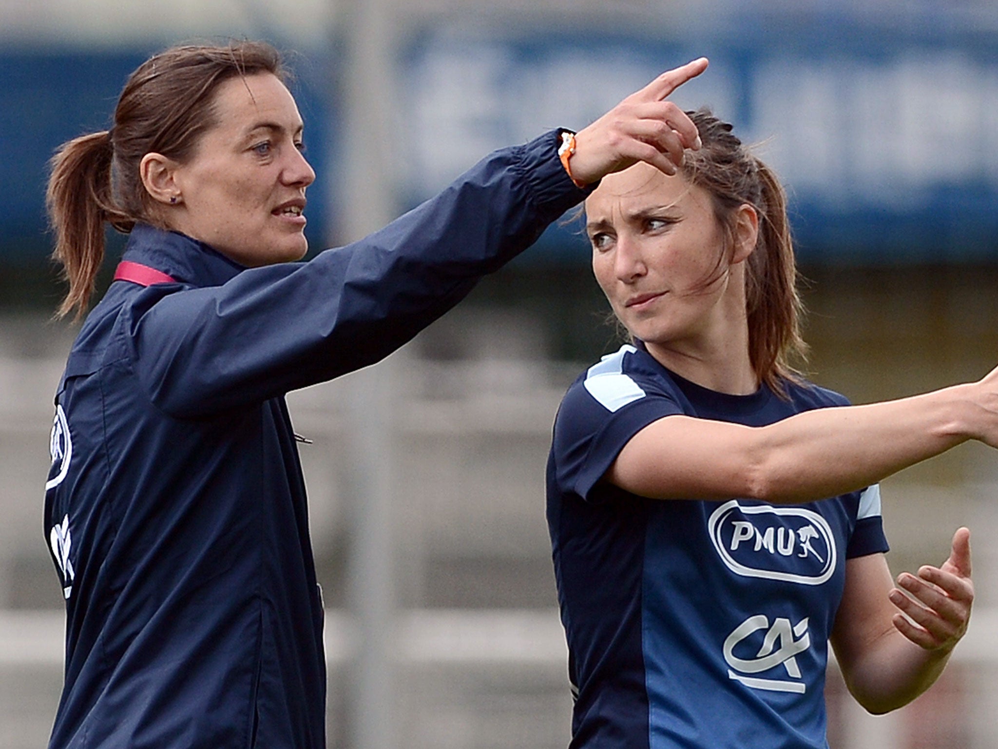 French women's national football team midfielder Gaetane Thiney (R) speaks with assistant coach Corine Diacre