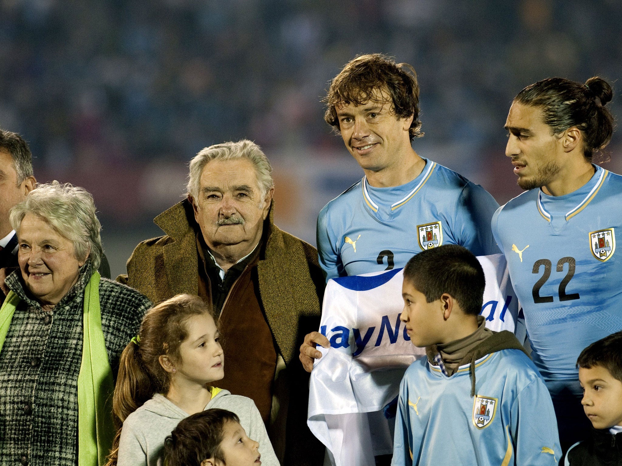 Uruguay's President Jose Mujica (3rd L) and his wife Lucia Topolansky (2nd L) stand next to Uruguay's footballers (L to R) Diego Lugano and Martin Caceres