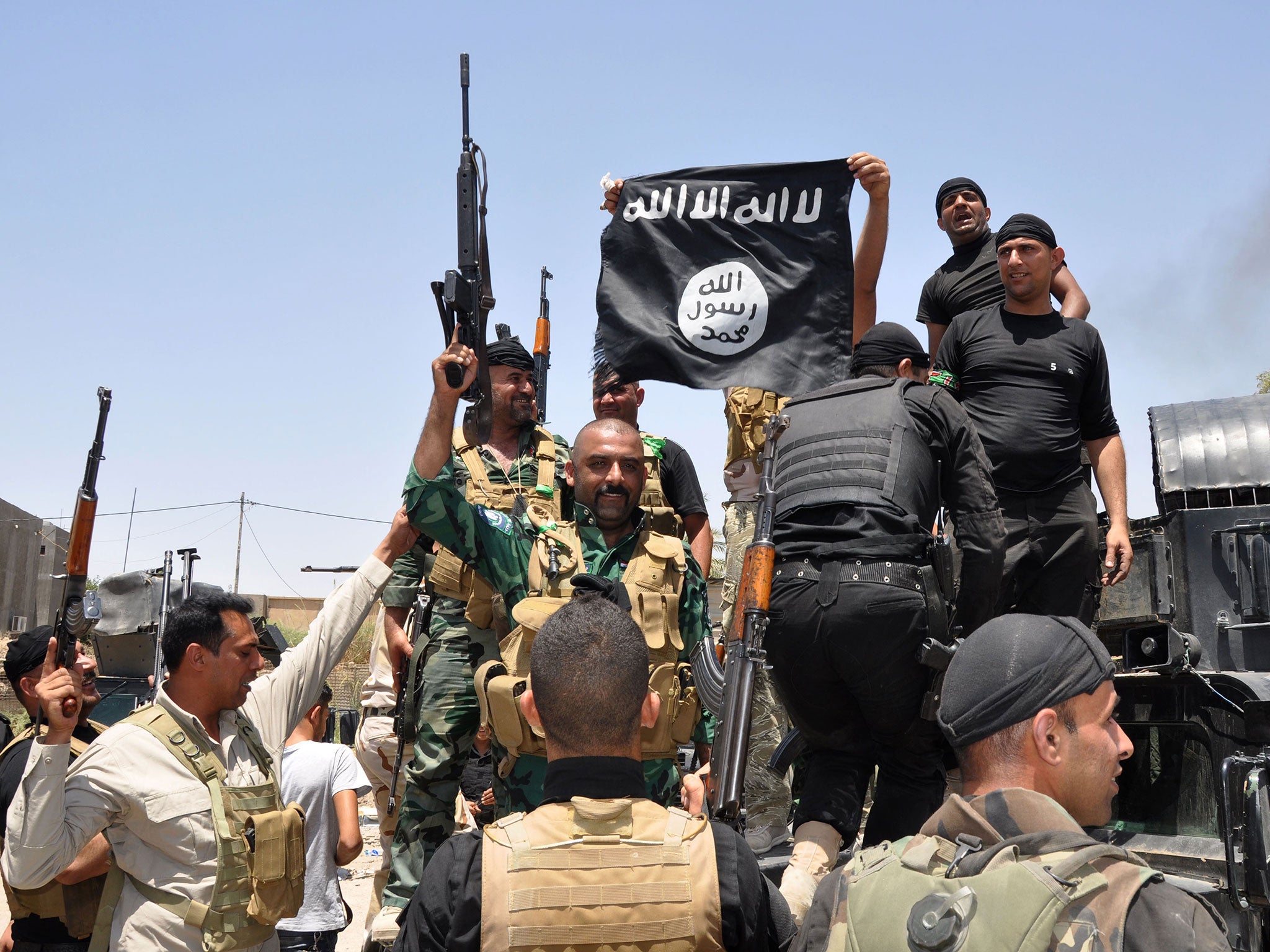 Iraqi security forces hold up a flag of the Isis group they captured during an operation to regain control of Dallah Abbas north of Baqouba, the capital of Iraq's Diyala province, 35 miles (60 kilometers) northeast of Baghdad