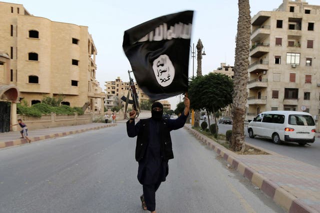 A member loyal to the Isis waves an Isis flag in Raqqa