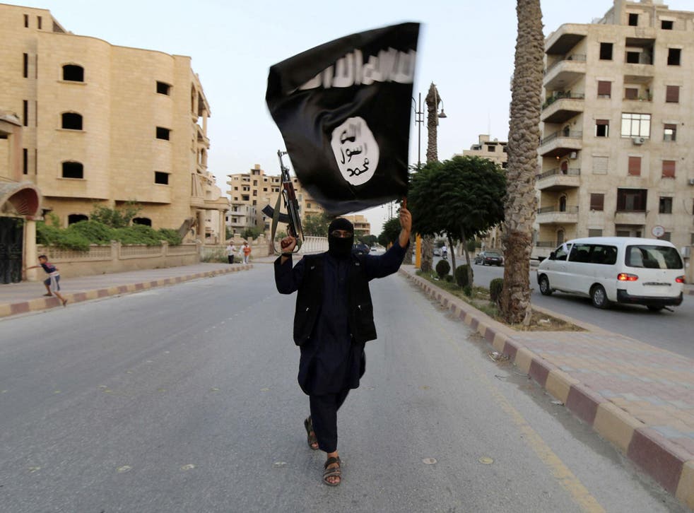 A member loyal to the Isis waves an Isis flag in Raqqa