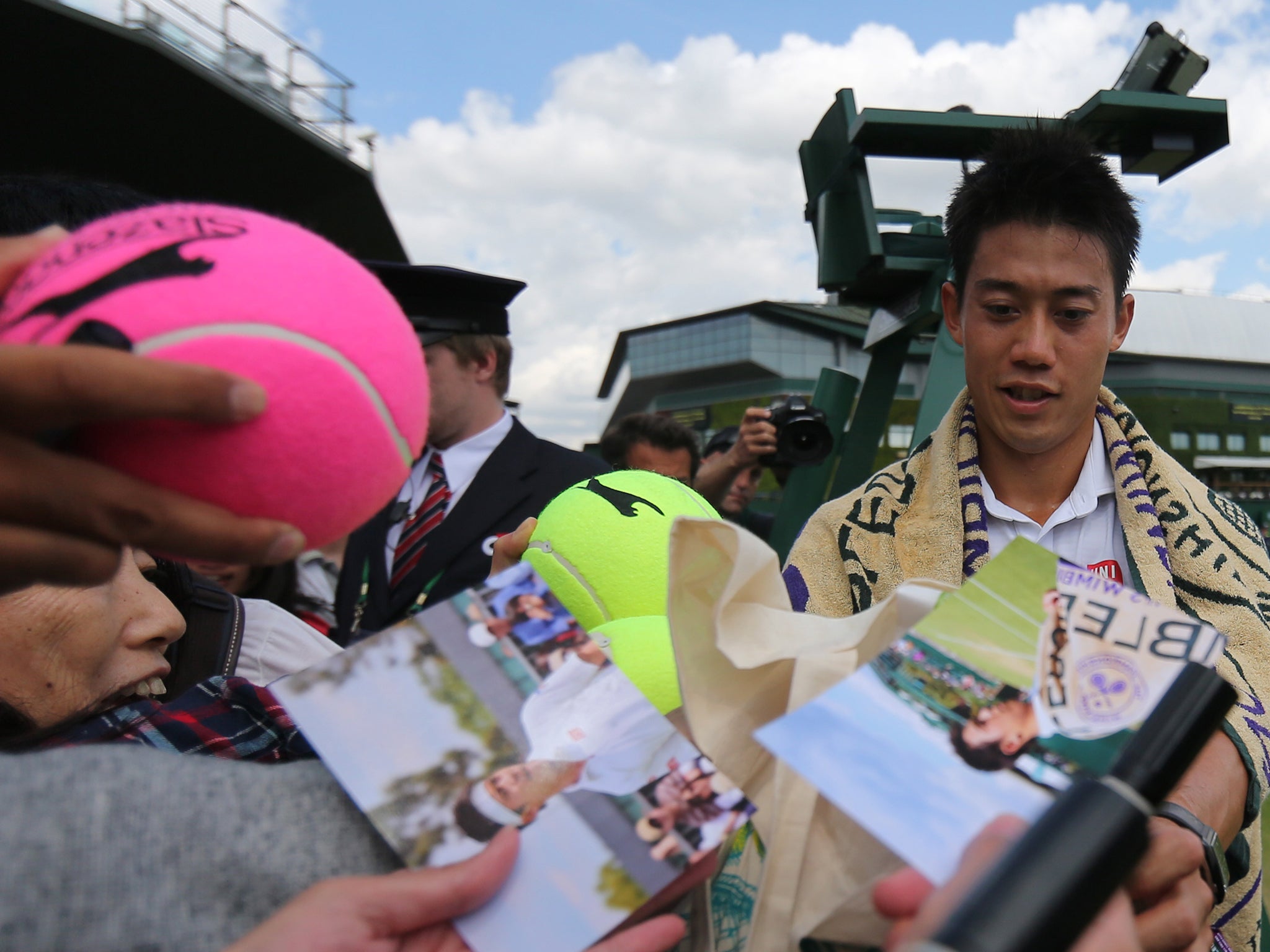 Japan's Kei Nishikori signs autographs after winning his men's singles third round match against Italy's Simon Bolelli