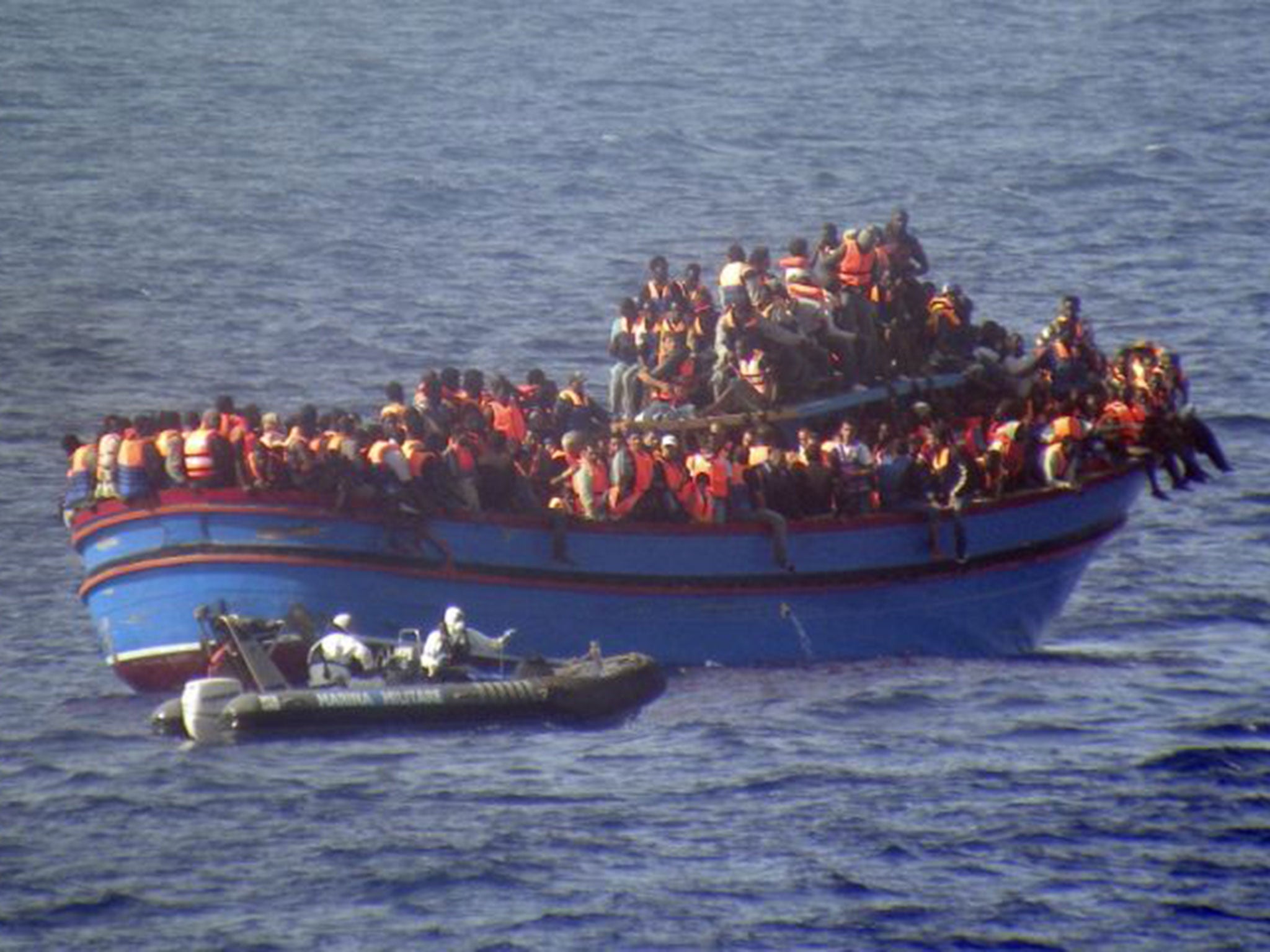 An Italian navy motor boat approaches a boat full of migrants making its way to Europe. The boat was carrying almost 600 people – but some 30 died during the journey