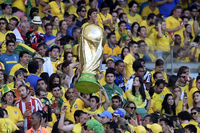 Brazilian fans hold a replica of the World Cup during extra-time in the Round of 16 football match between Brazil and Chile at The Mineirao Stadium