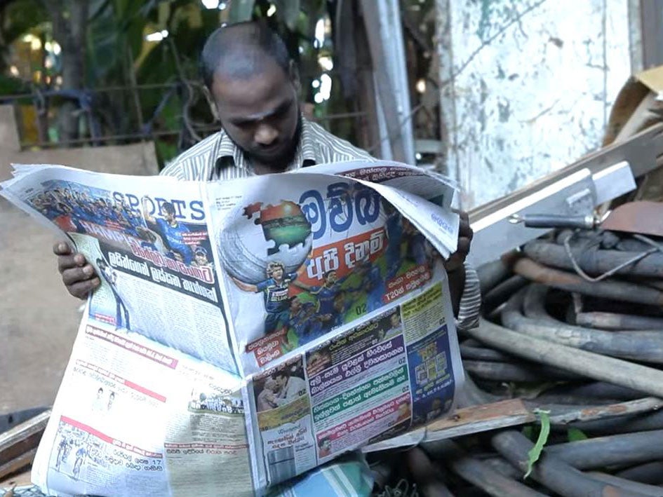A man reading the special mosquito-repellent Mawbima paper