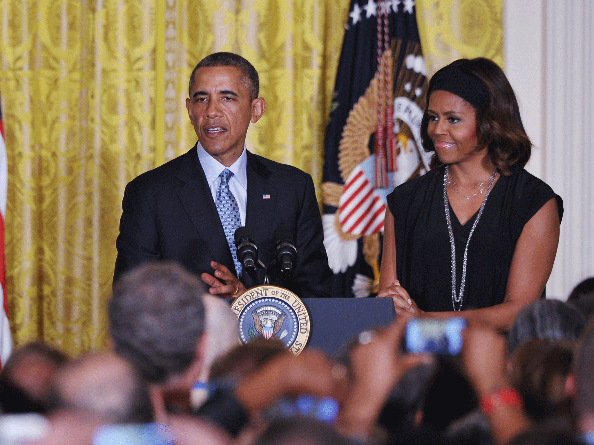 US President Barack Obama speaks during a reception celebrating LGBT Pride Month as First Lady Michelle Obama watches on June 30, 2014 in the East Room of the White House in Washington, DC