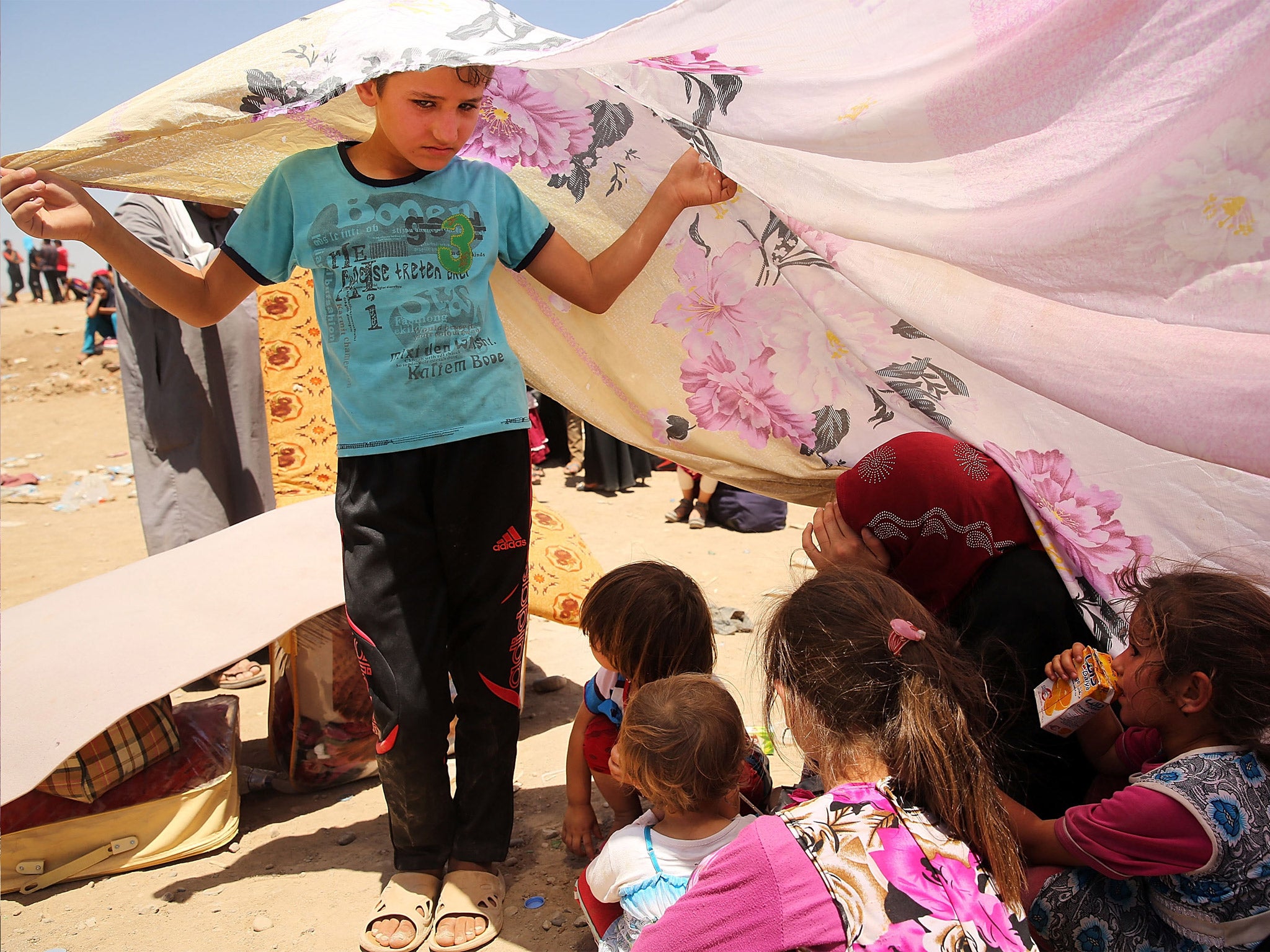 Iraqis who have fled the recent fighting wait in hope of entering a refugee camp in Khazair
