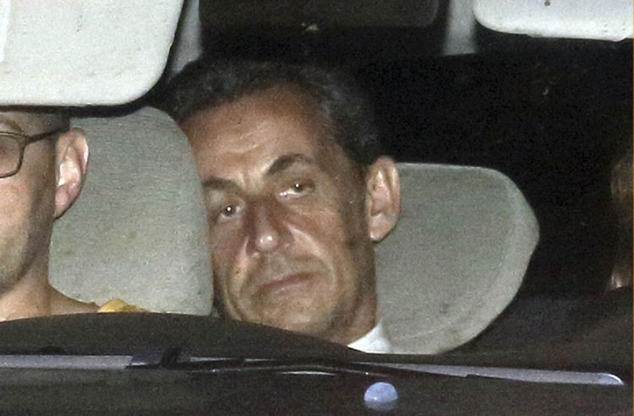 Nicolas Sarkozy arrives with police by car at the financial investigation unit in Paris to be presented to a judge
