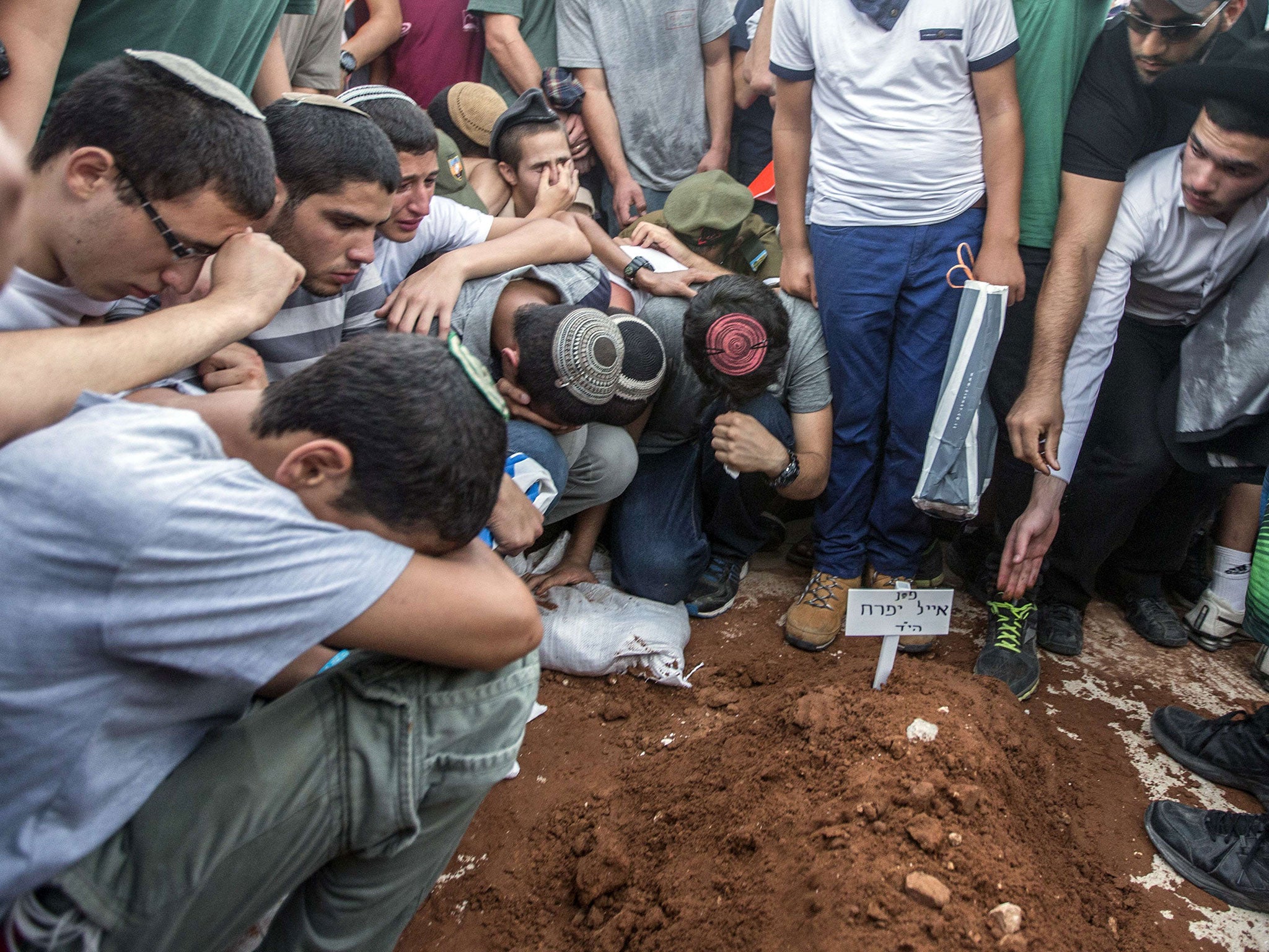 Relatives and friends gather around a grave, as Gilad Shaer, 16, Naftali Frenkel, 16, and Eyal Ifrach, 19, are buried side-by-side in the central Israeli town of Modiin