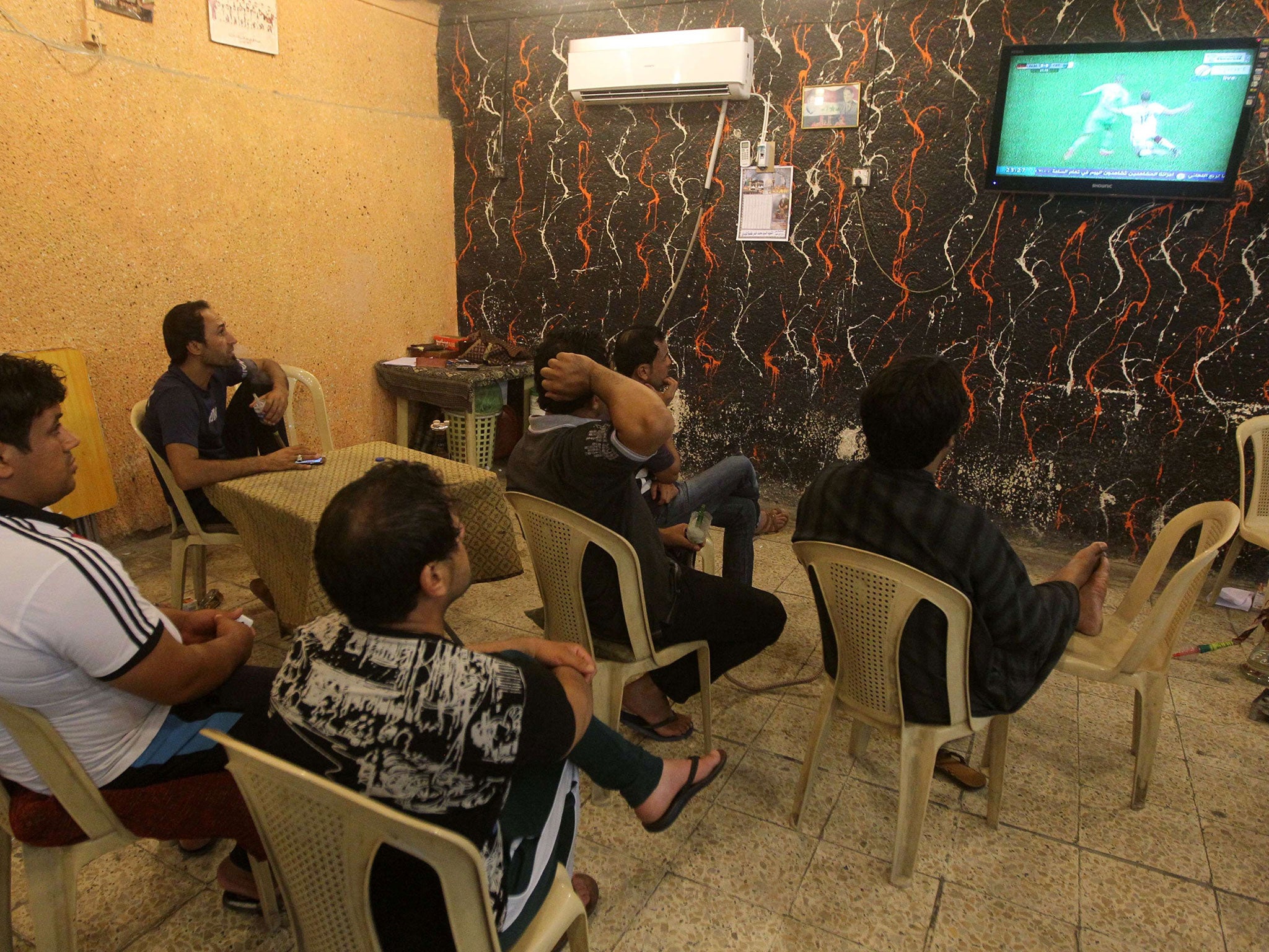 Iraqi Raad Abdulhussein (centre) and his friends sit watching on the World Cup match between Algeria and Germany at the "Facebook" cafe in the Iraqi capital Baghdad