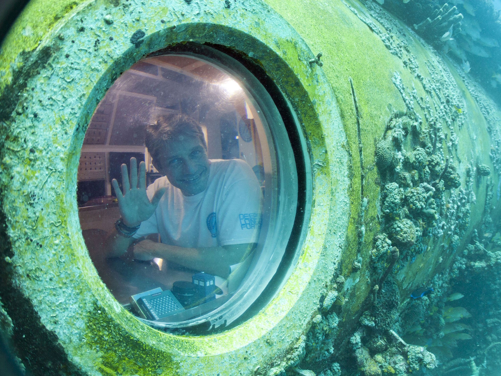 Fabien Cousteau waves from inside Aquarius Reef Base, a laboratory 63 feet below the surface in the waters off Key Largo, in the Florida Keys