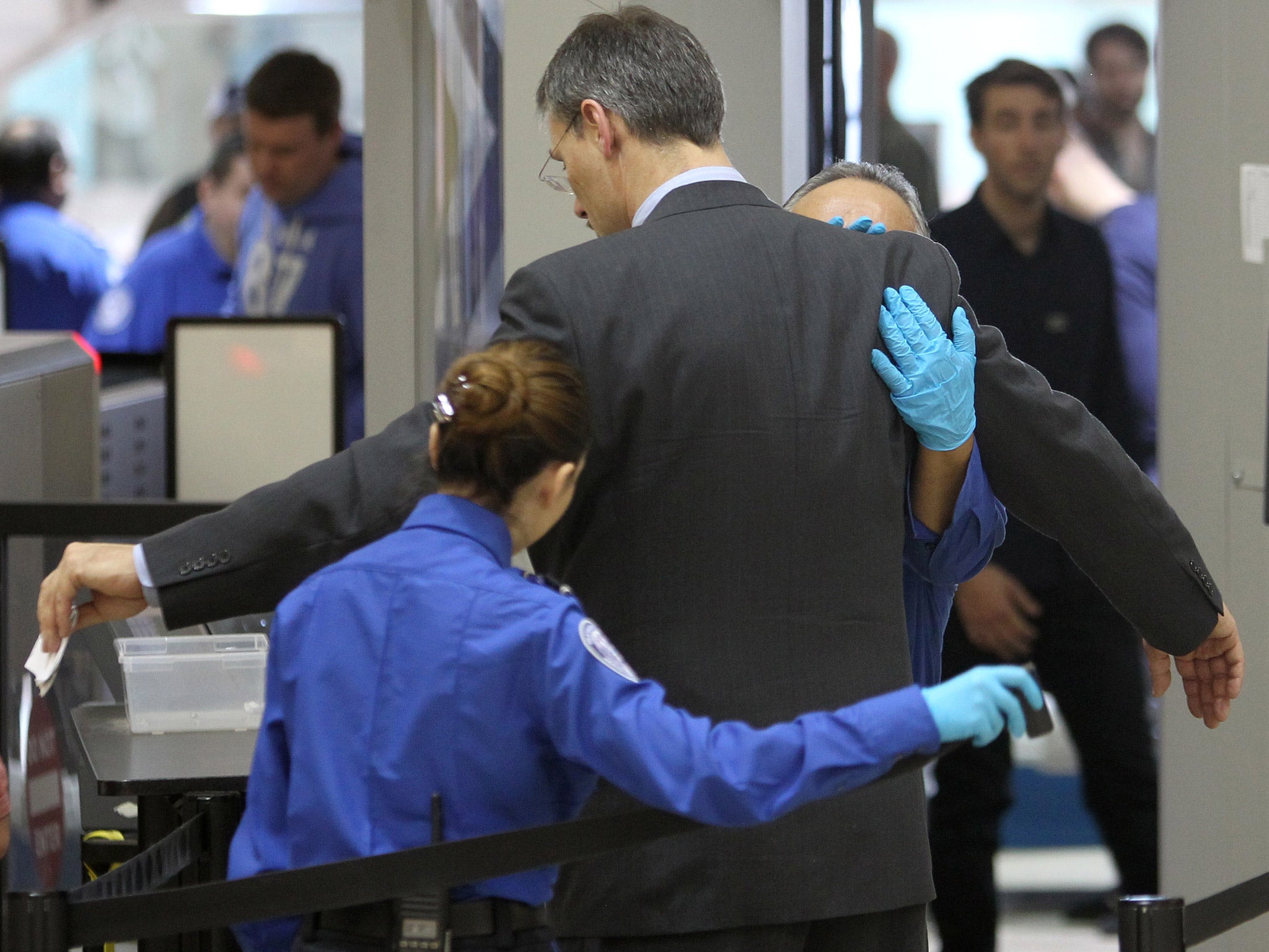 A plane passenger is patted down after passing through a full-body scanner at Los Angeles International Airport