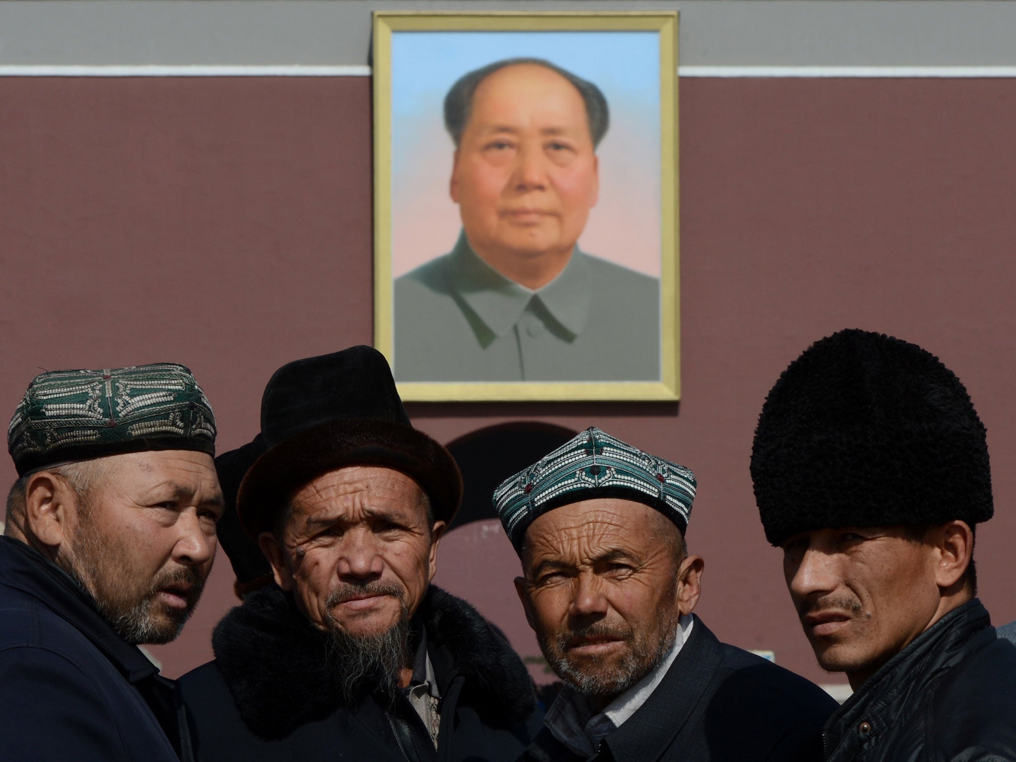 Chinese muslims known as 'Uighurs' from Xinjiang Province pose for photos in front of a portrait of Mao Zedong before the opening session of the Chinese People's Political Consultative Conference (CPPCC) at the Great Hall of the People in Beijing on March 3, 2013
