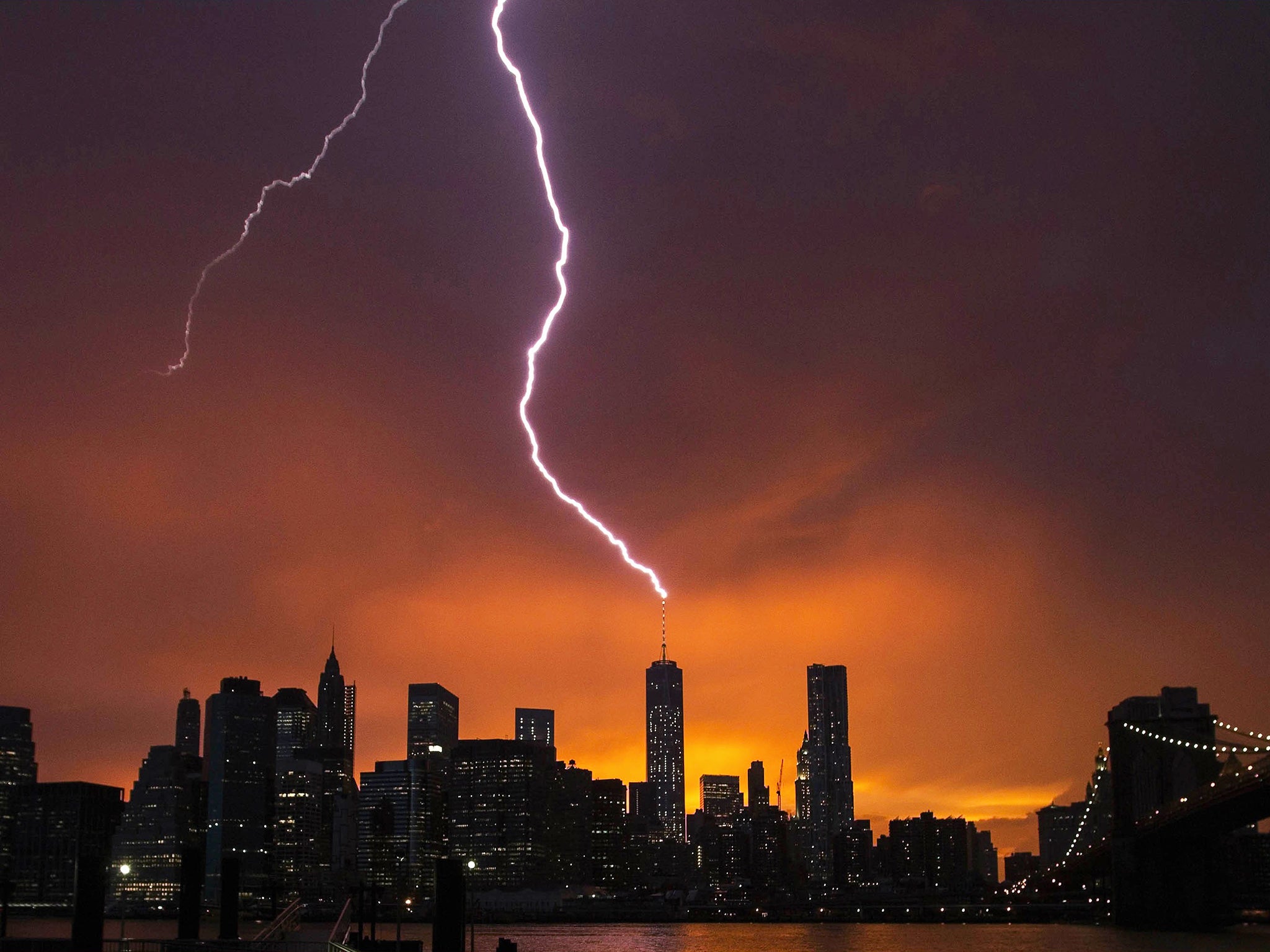 Lightning strikes One World Trade Center in Manhattan as the sun sets behind the city after a summer storm in New York