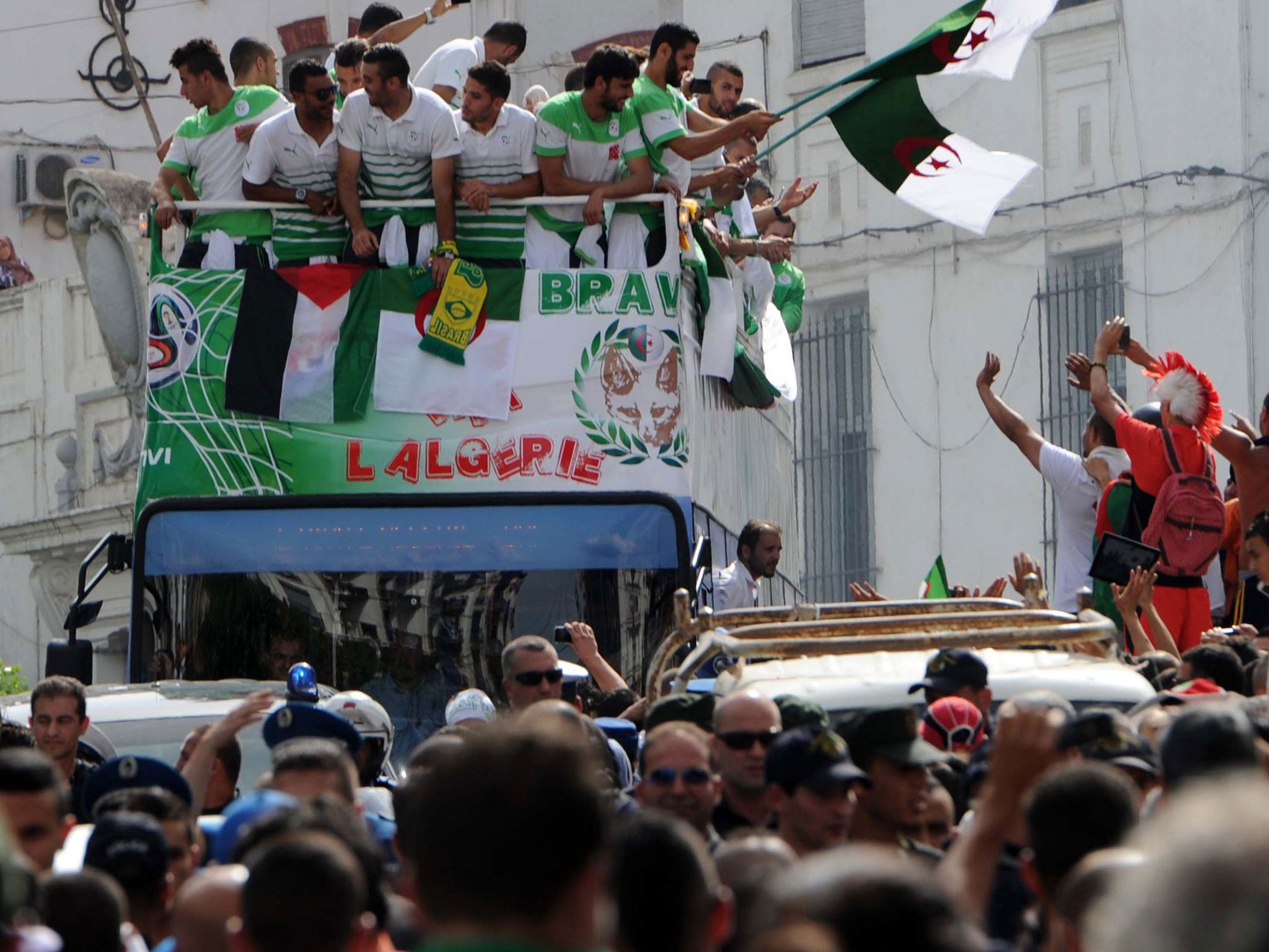 The Algeria World Cup team on their open-bus tour through Algiers. A Palestinian flag can be seen draped from the front of the bus