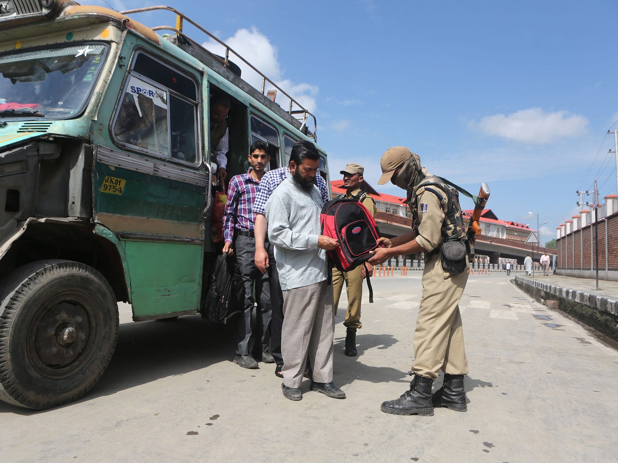 An Indian paramilitary soldier checks the bag of Kashmiri man during a search operation in Srinagar