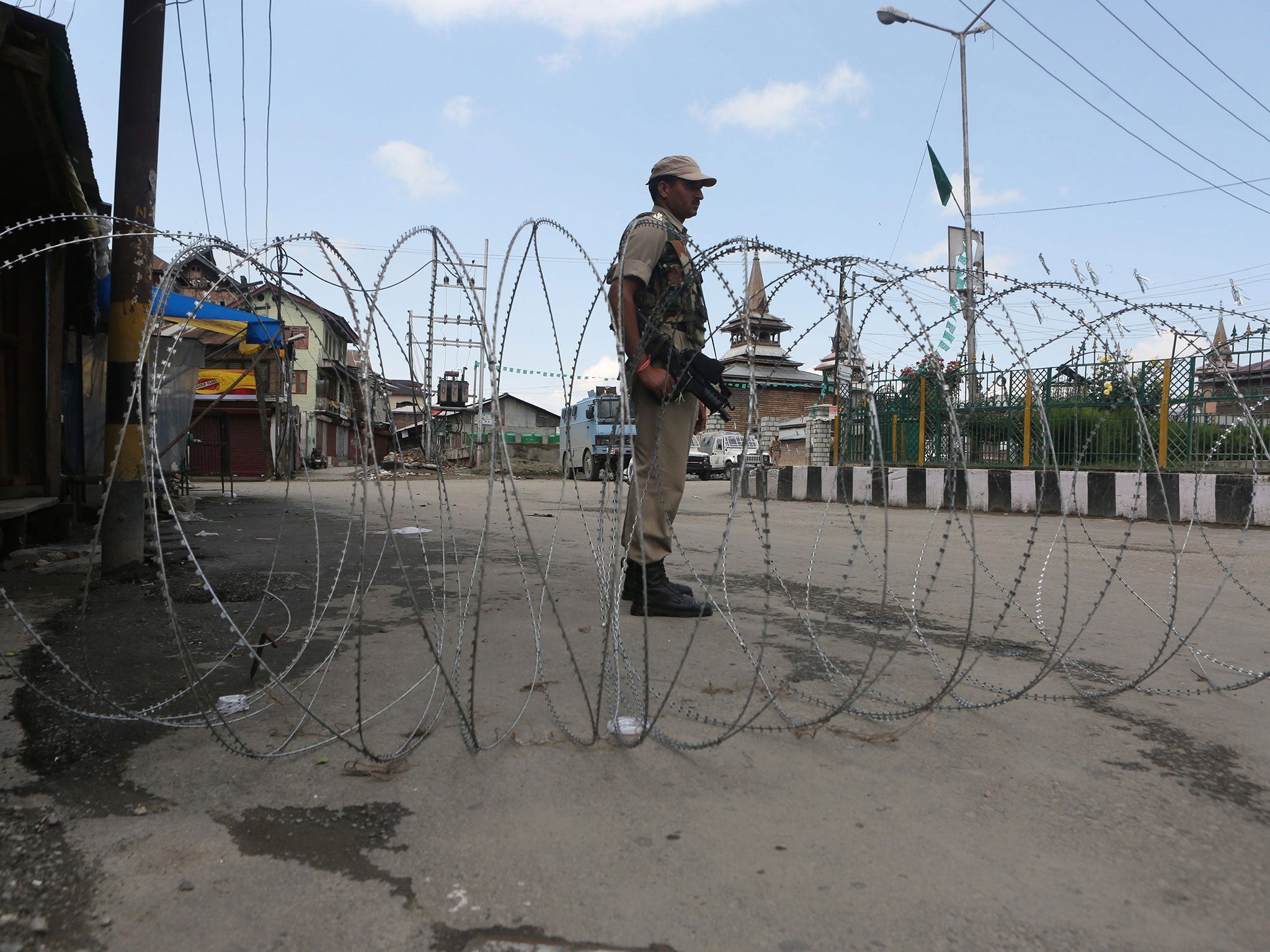 An Indian paramilitary soldier stands guard near barbed wire setup as barricade during restrictions in downtown area of Srinaga