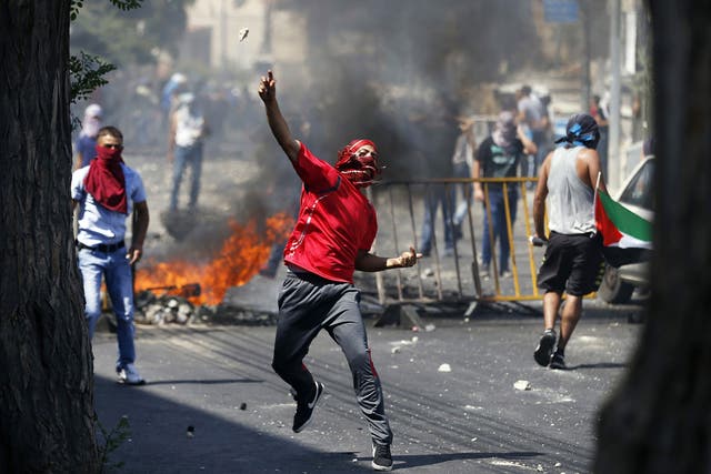 A Palestinian throws a stone during clashes with Israeli police after prayers on the first Friday of the holy month of Ramadan in the East Jerusalem