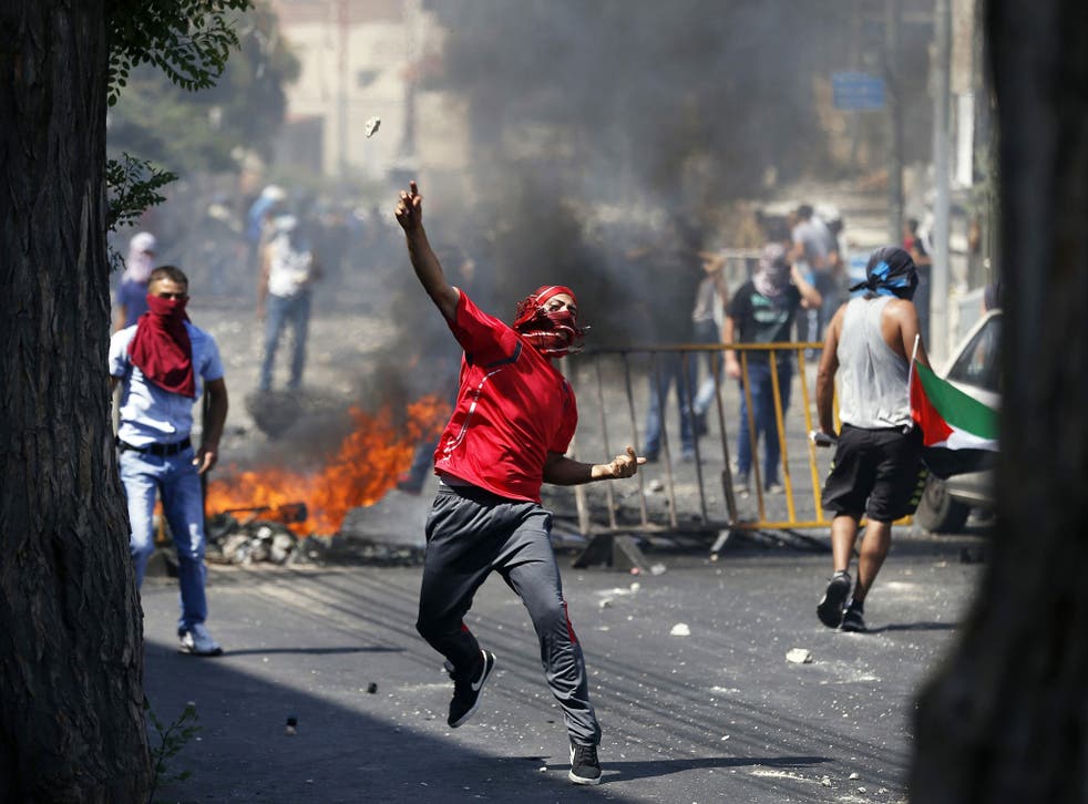 A Palestinian throws a stone during clashes with Israeli police after prayers on the first Friday of the holy month of Ramadan in the East Jerusalem