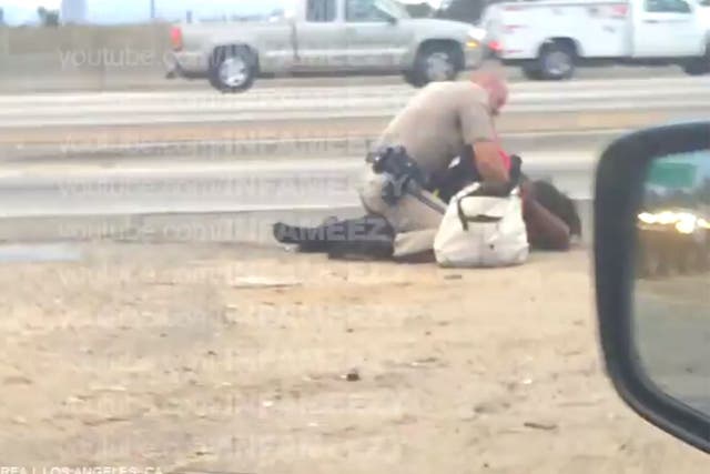 The footage appears to show the officer punching the woman while she is on the floor