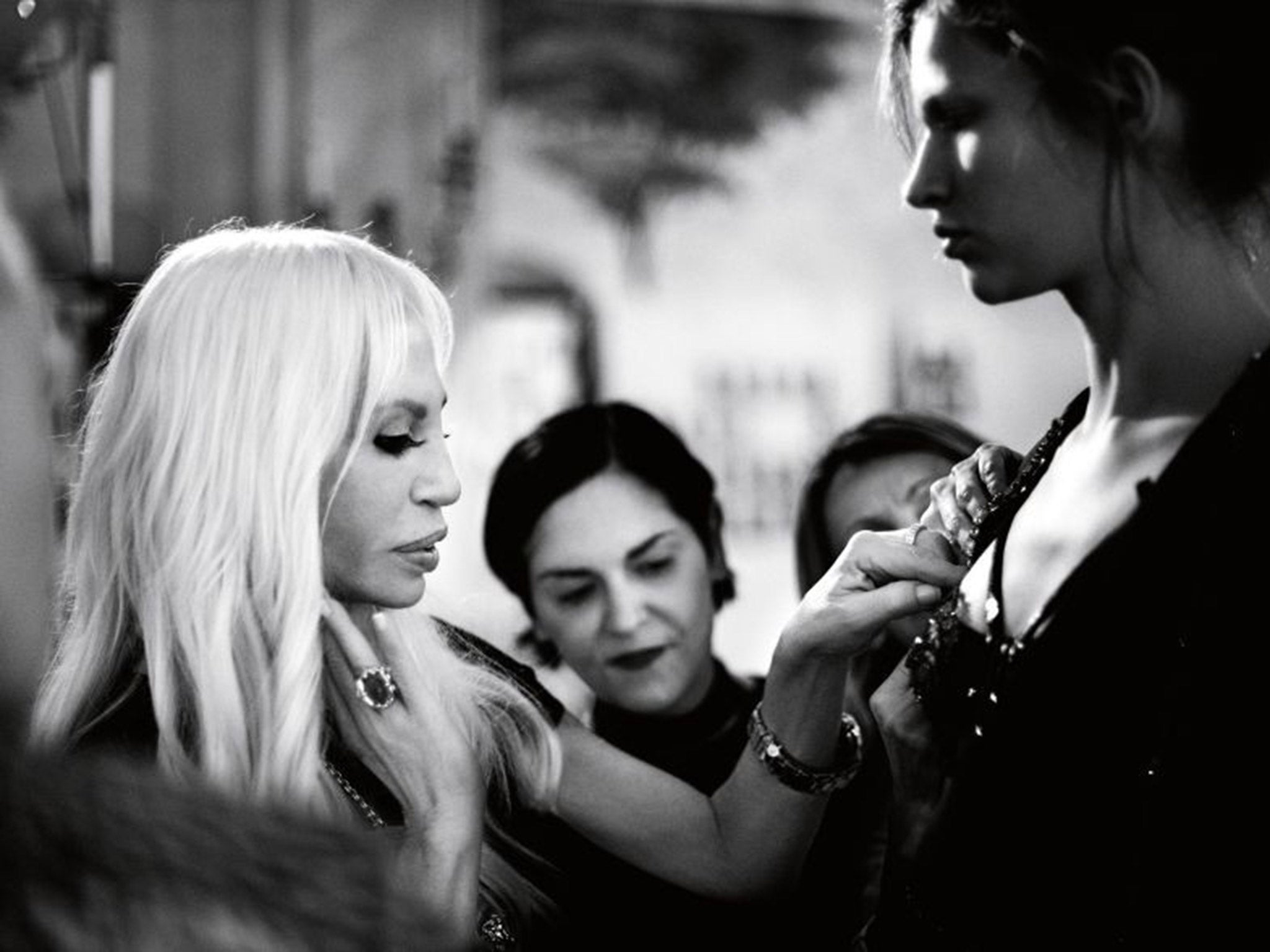 Donatella Versace adjusts a model's intricate clothing during her couture collection