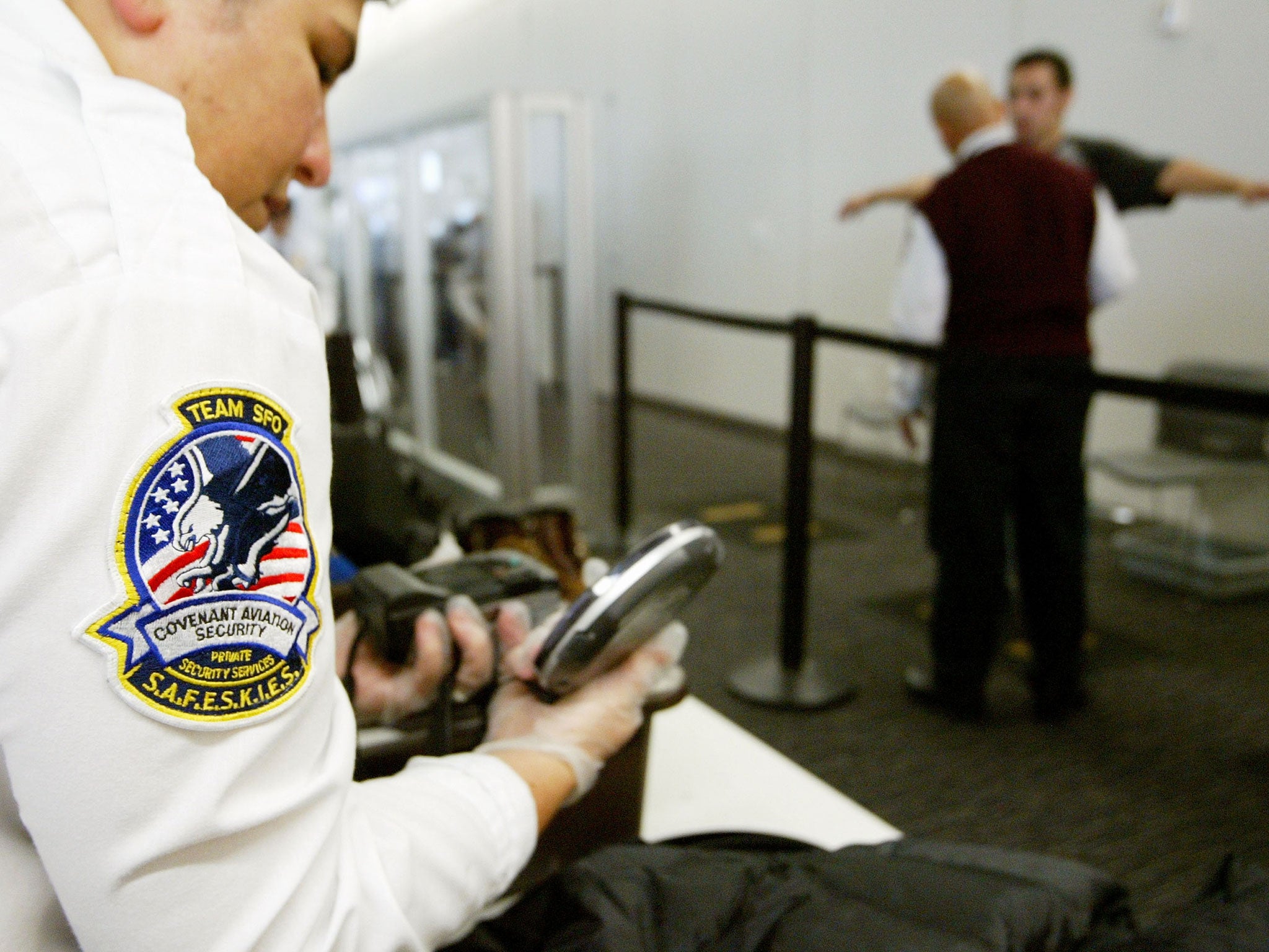 File: A San Francisco baggage screener inspects an electronics device, as the Department for Transport issued new guidelines for all US-bound flights