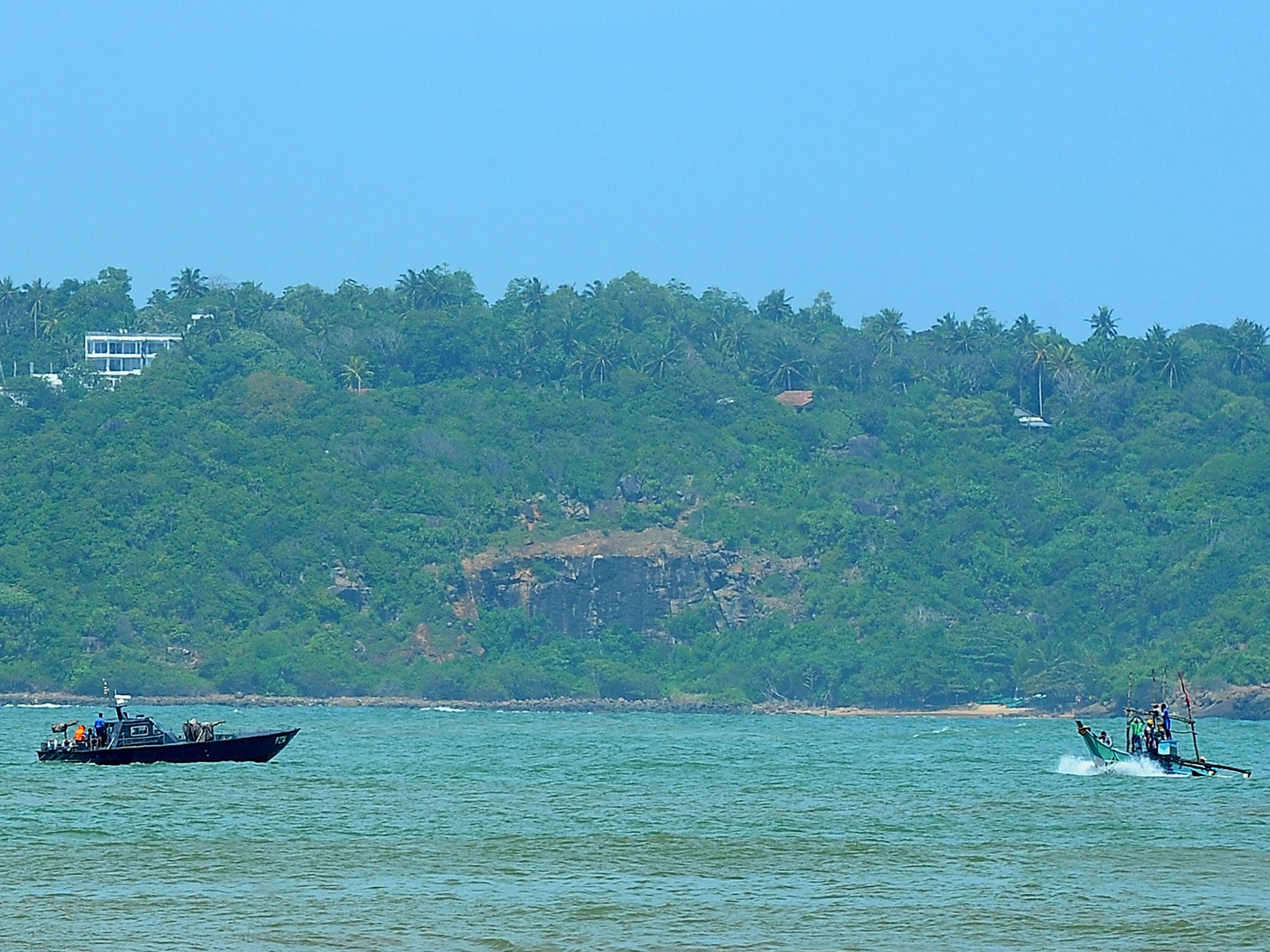 A Sri Lankan navy boat (L) patrols after Australia transferred 41 would-be asylum seekers whose boat was turned away at the southern port of Galle 