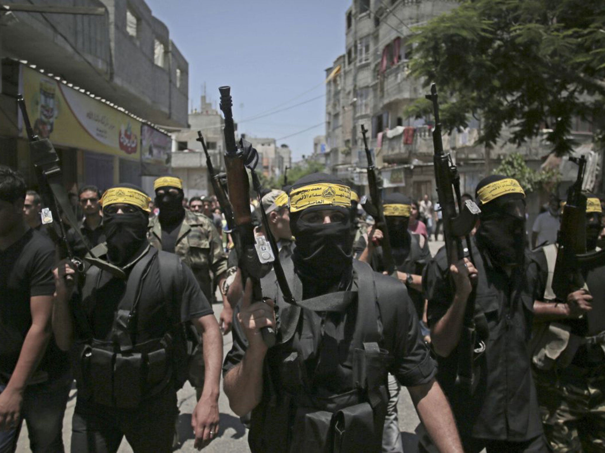 Masked Palestinian militants march with guns as they attend the funeral of two Fatah militants killed by an Israeli airstrike