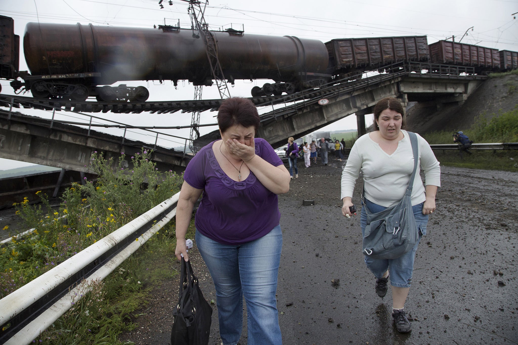 People walk under a destroyed railroad bridge over a main road leading into the east Ukraine city of Donetsk