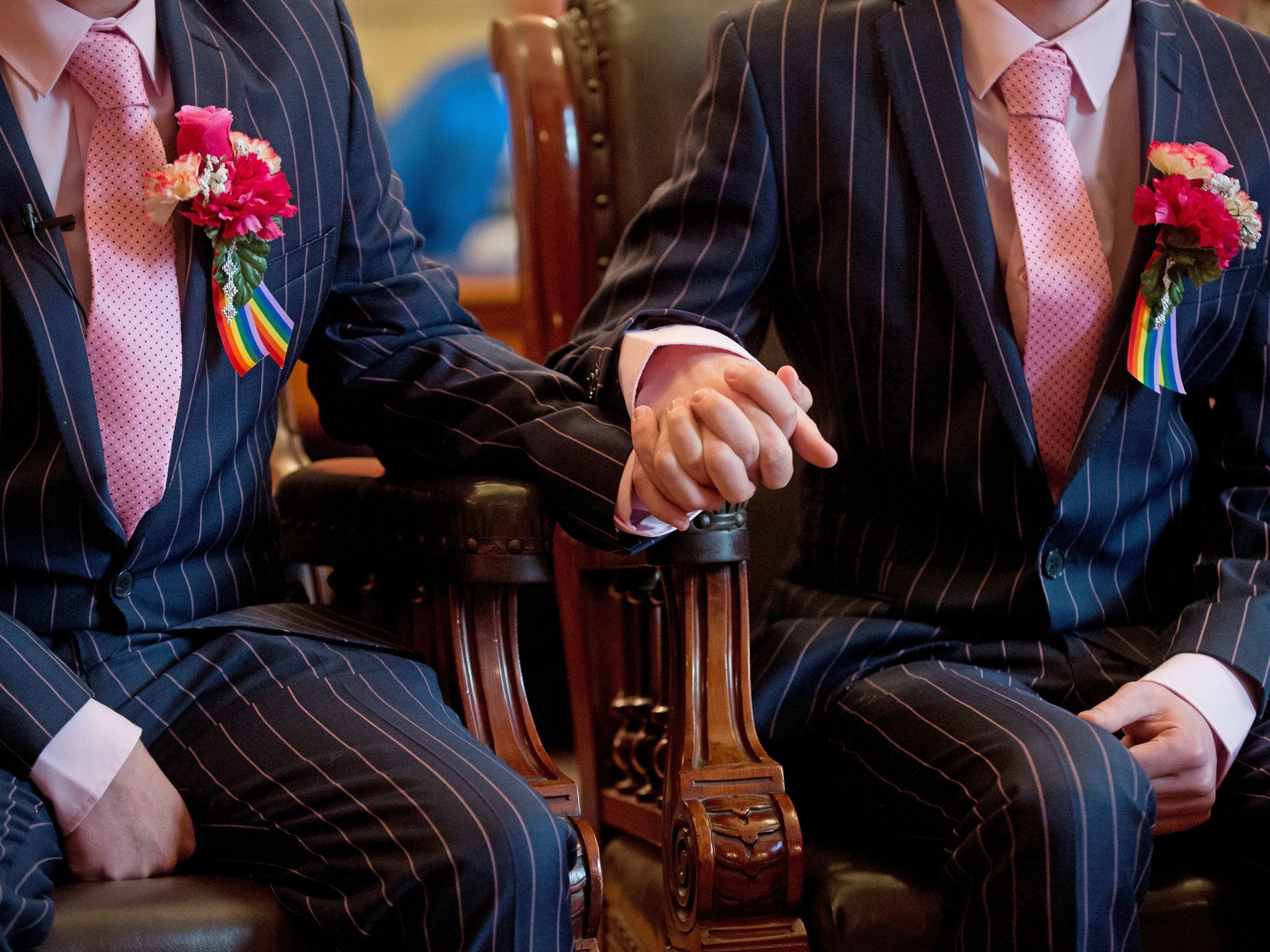 A couple hold hands during their wedding ceremony in Brighton, southern England