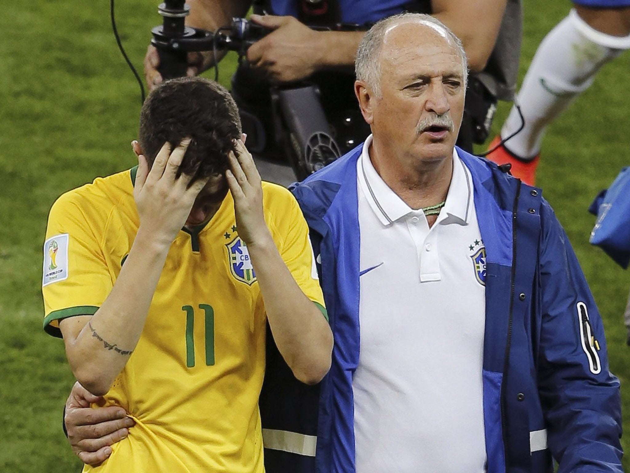 Brazil's head coach Luiz Felipe Scolari leads player Oscar off the pitch after the FIFA World Cup 2014 semi final match between Brazil and Germany at the Estadio Mineirao in Belo Horizonte, Brazil