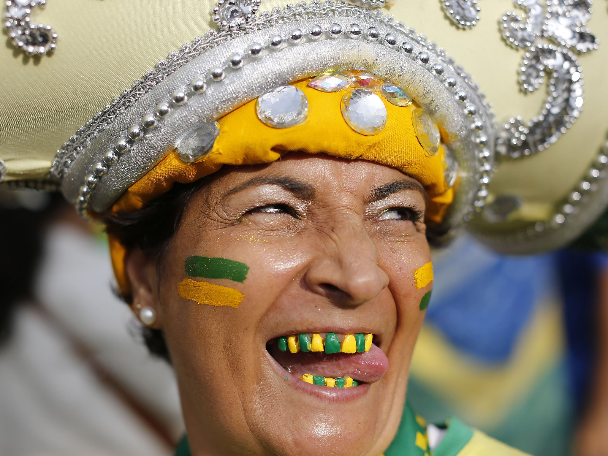 A Brazil soccer fan with her teeth decorated in the colors of her soccer team poses for a photo before watching the World Cup semifinal match between Brazil and Germany on a live telecast inside the FIFA Fan Fest area on Copacabana beach in Rio de Janeiro