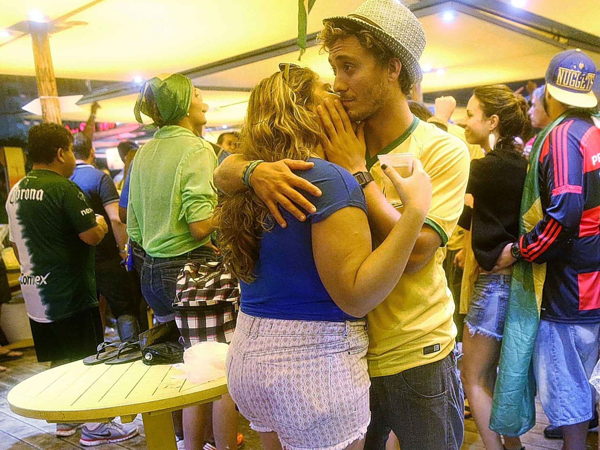 Two Brazilian fans embrace in a bar on Copacabana beach as their country’s humiliating 7-1 defeat by Germany sinks in