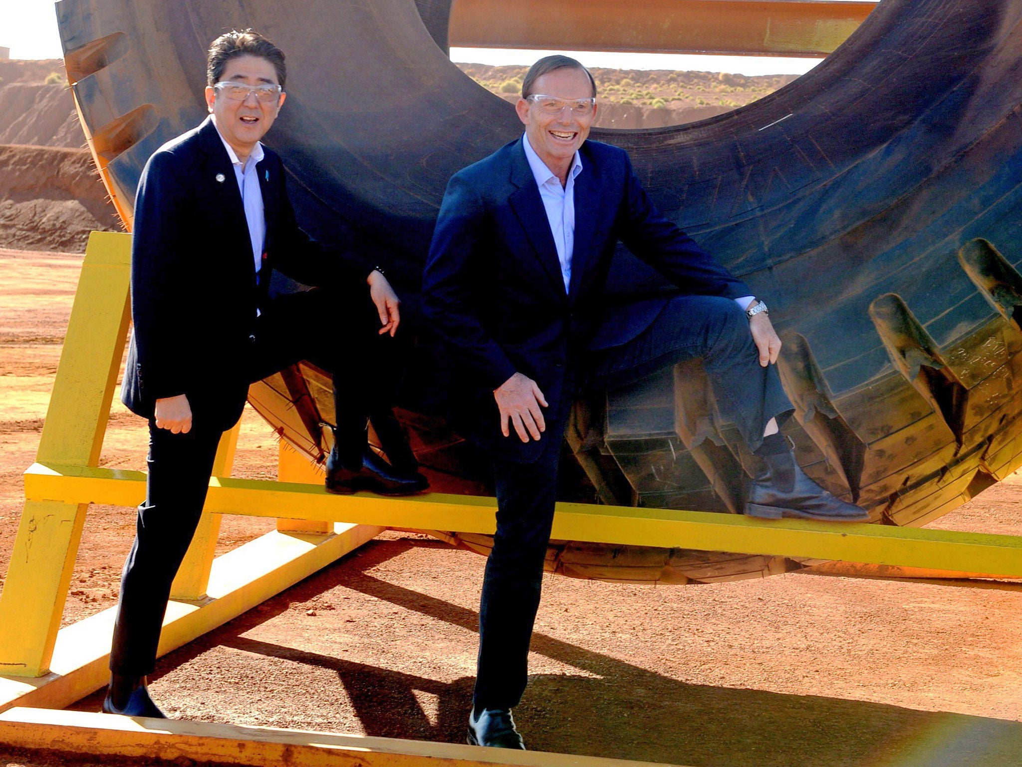 Australian Prime Minister Tony Abbott (R) and Japanese Prime Minister Shinzo Abe pose for a photograph next to a haulage truck tyre during a tour of Rio Tinto's West Angelas iron ore mine in Pilbara, Western Australia on July 9, 2014