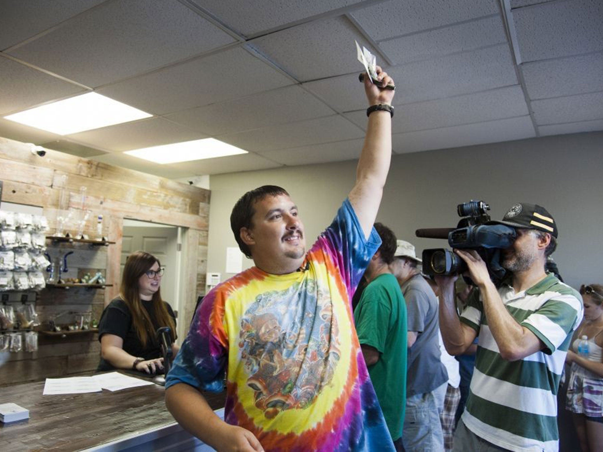 Mike Boyer turns to the crowd outside, showing off the 4 grammes of marijuana he bought as the first in line to legally purchase marijuana at Spokane Green Leaf