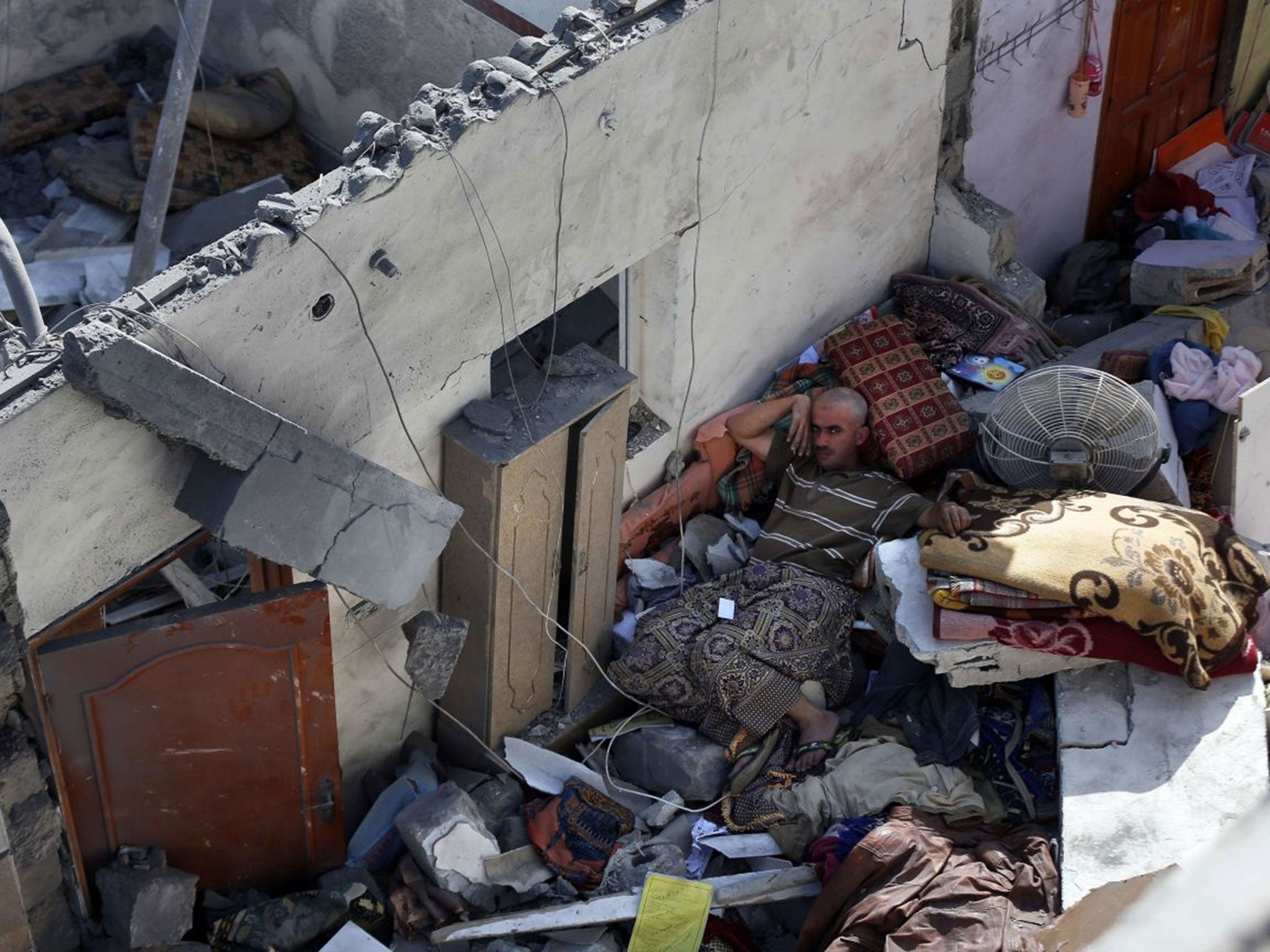 A Palestinian man lies amid the rubble of his house following an Israeli air strike in Khan Yunis. (AFP)