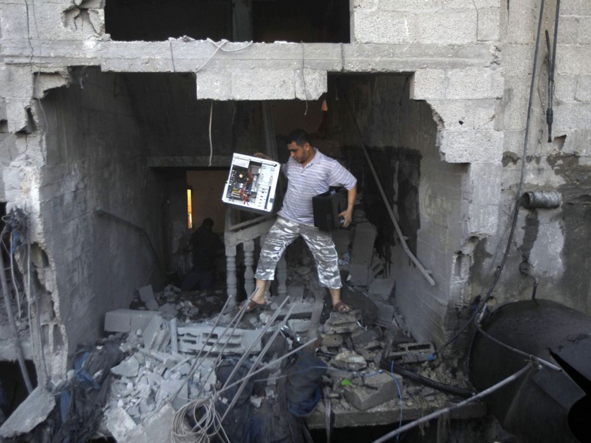 A Palestinian man removes a computer from the rubble of the Ghanam family home after it was targeted in an air raid on Rafah on 11 July 11