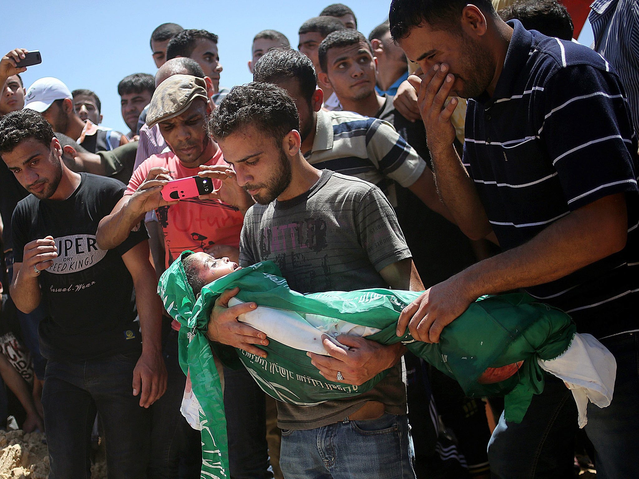 Palestinians carry the body of three-year-old Mohammed Mnassrah who was killed along with his parents and brother in an airstrike, during his funeral in Al Maghazi refugee camp in the eastern Gaza Strip